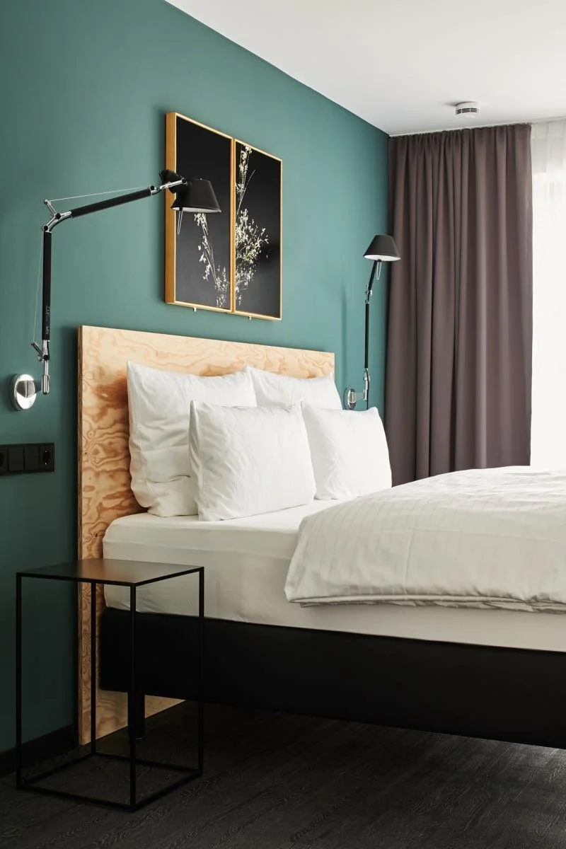 Modernes Design-Zimmer im Winterfeld Guest House Bodenmais mit stilvollem Boxspringbett, Salbeigrüner Wand und minimalistischer Beleuchtung