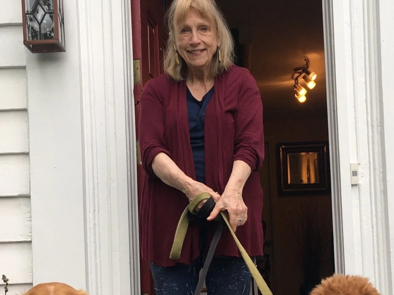 Woman standing in a doorway holding dog leashes