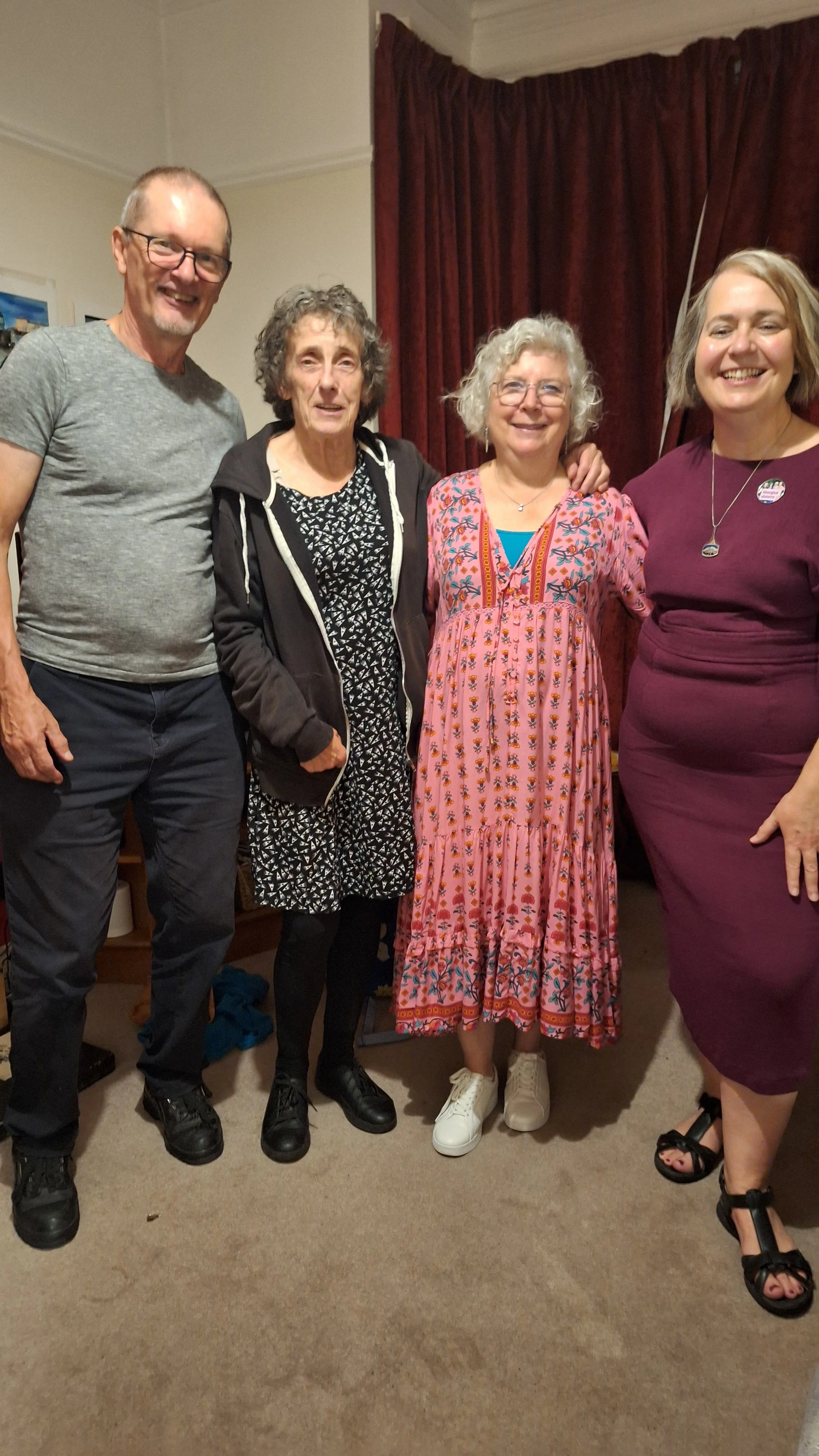 David Herring, Helen Kay, Louise Walker and Ceri Morgan standing indoors near a red curtain, smiling and posing for the photo after Ceri's launch of Unstuck