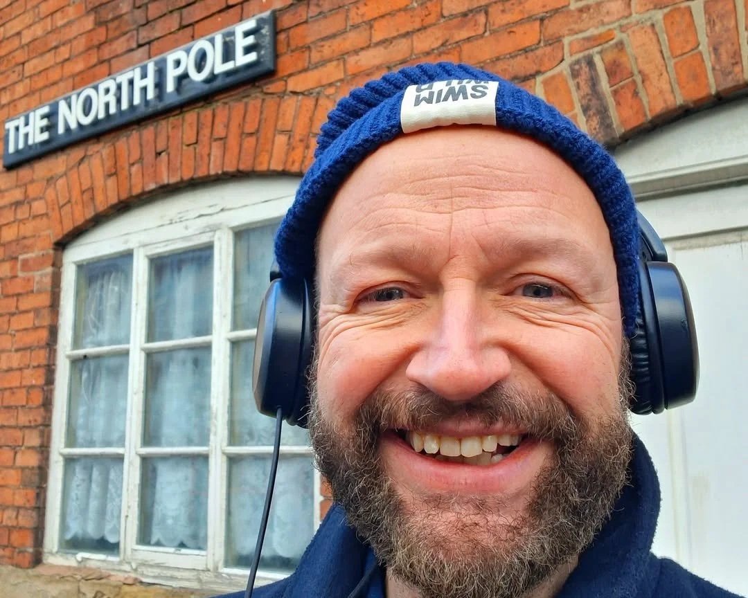 Christopher James, the author of The Ice Sonnets, standing outside a building with the sign on it for 'The North Pole'.