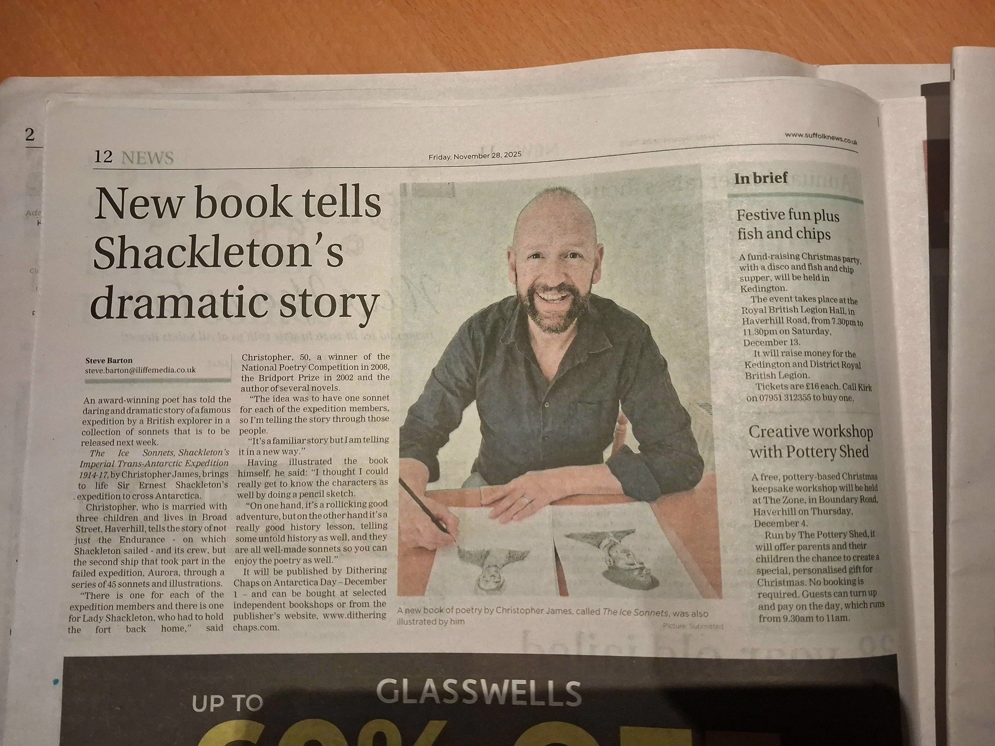 A newspaper article titled 'New book tells Shackleton’s dramatic story' featuring a photograph of a man with a beard, sitting at a table with a book and a glass of water. The article discusses a new book by Christopher James about Sir Ernest Shackleton's expedition.