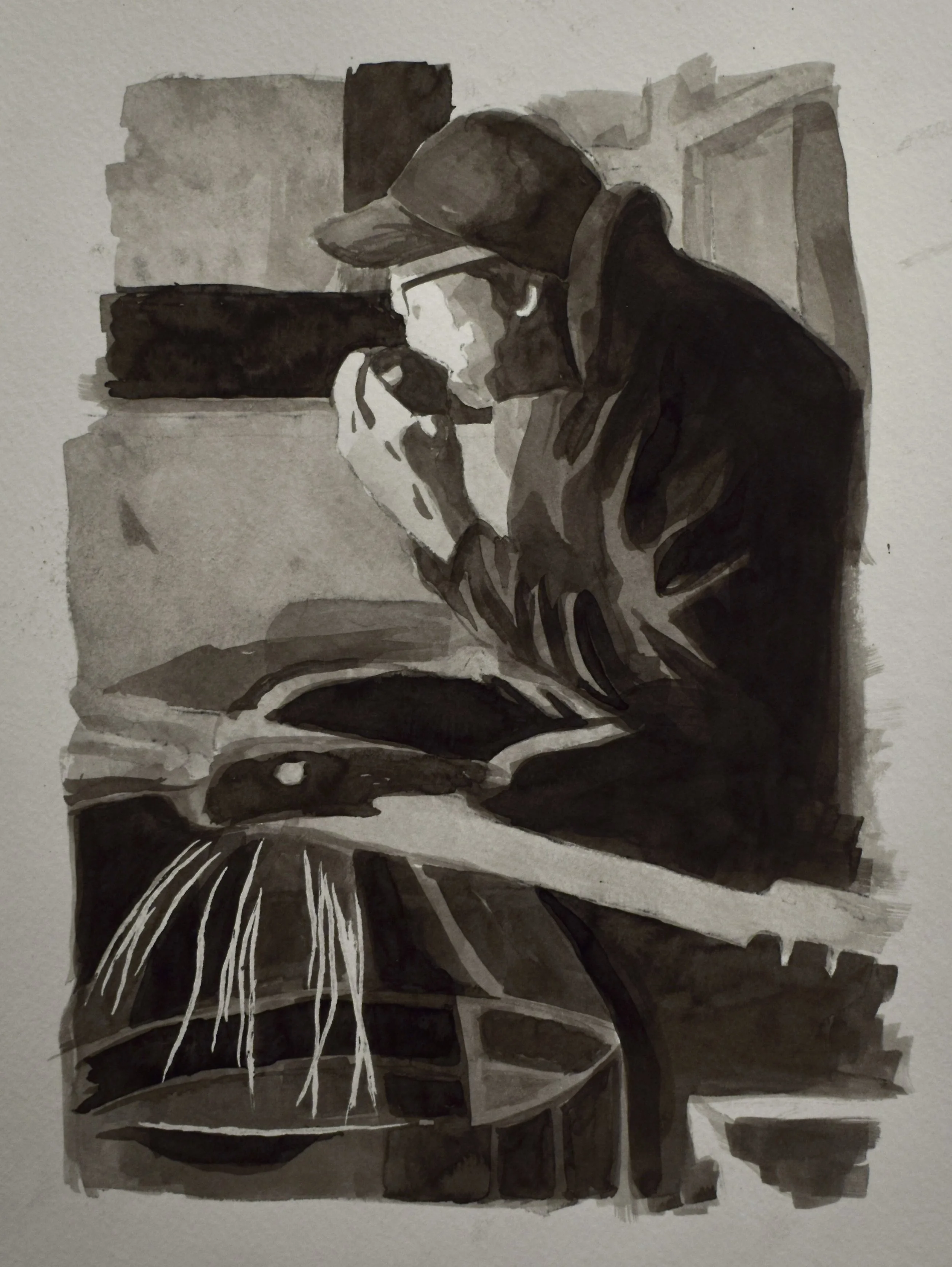 A person wearing a baseball cap and glasses, sitting at a table, looking at a phone.