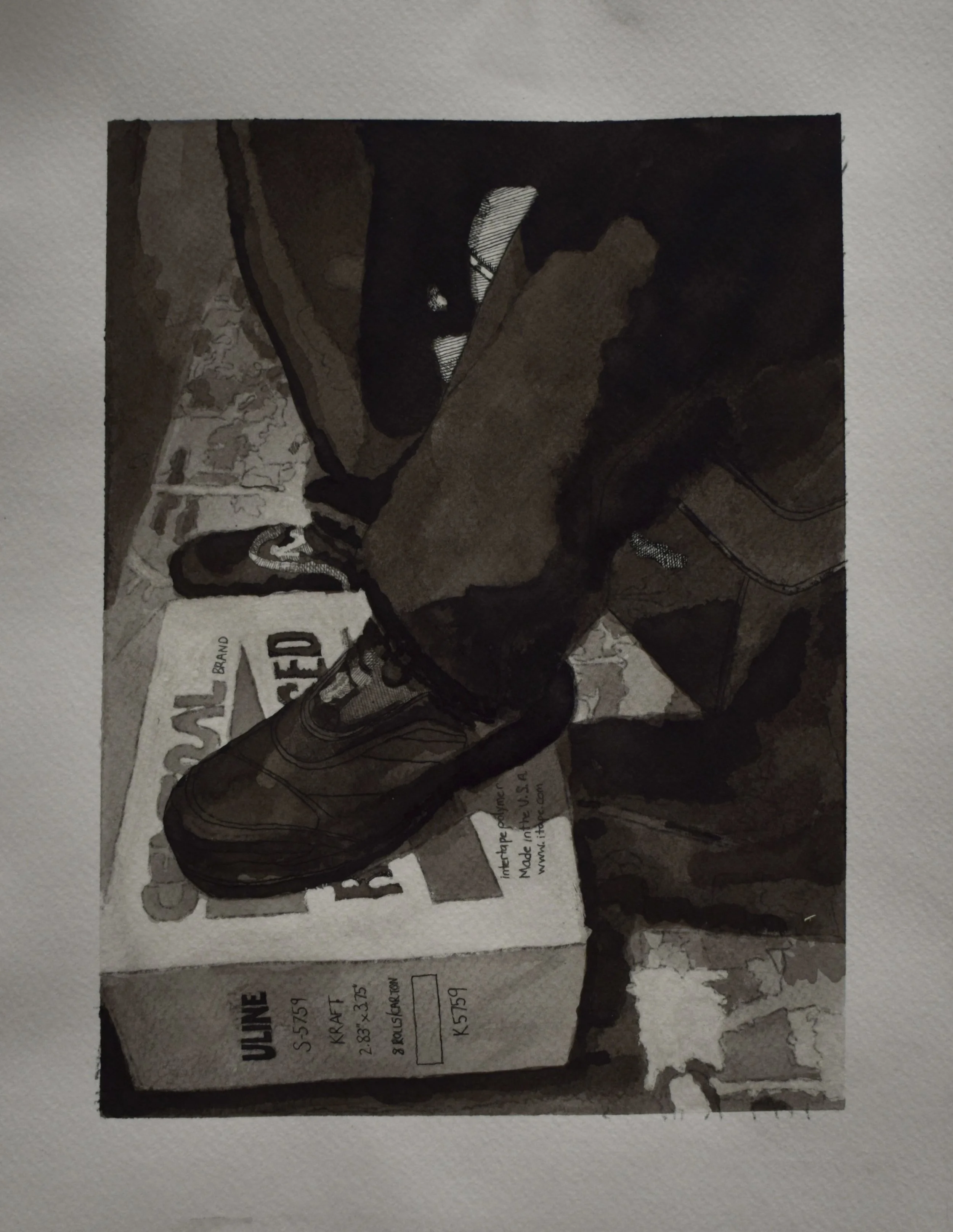 A pair of black athletic shoes placed on top of a white shoebox with black text, set on a textured surface.