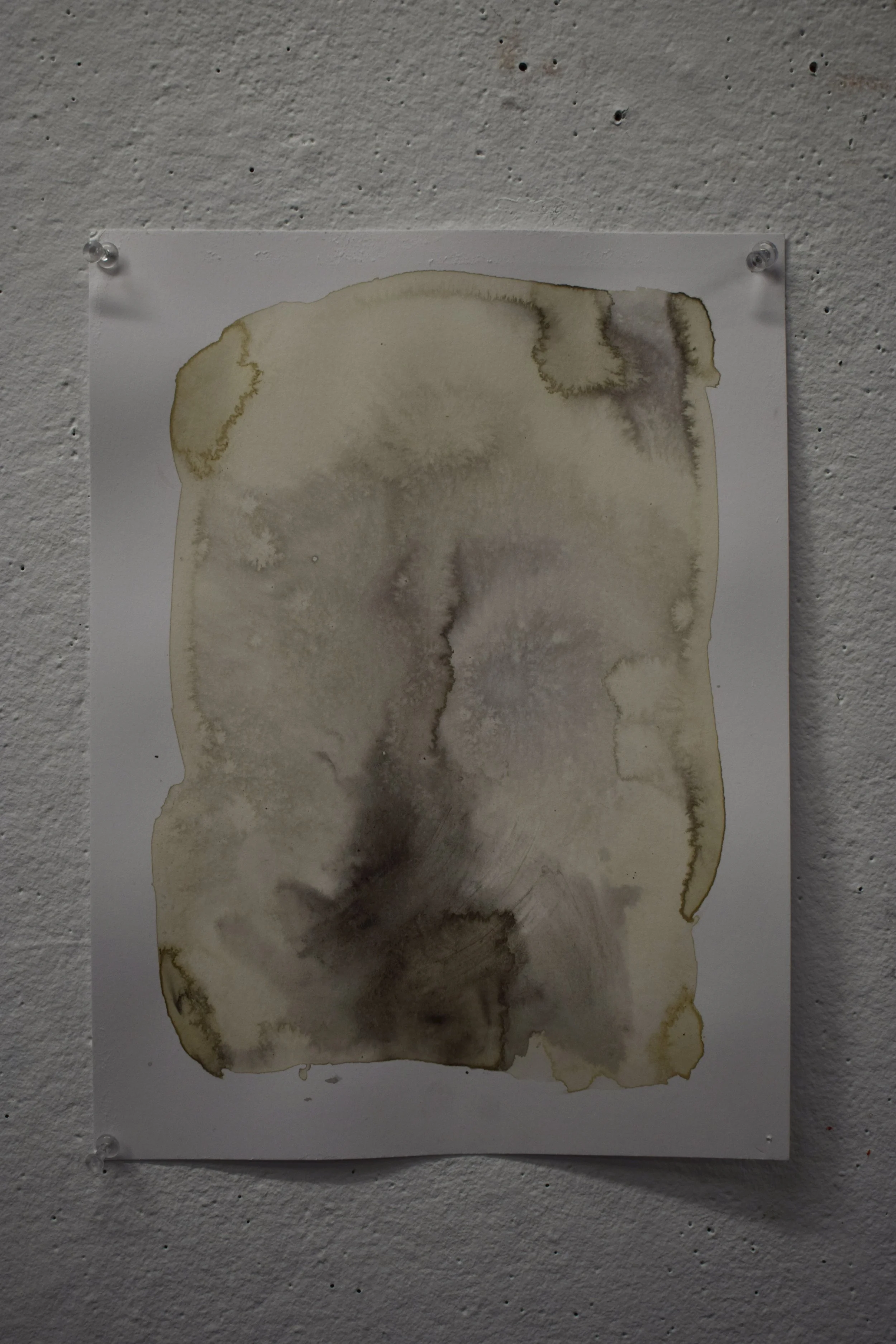 Abstract watercolor painting on paper with beige, brown, and gray tones, pinned to a white textured wall.