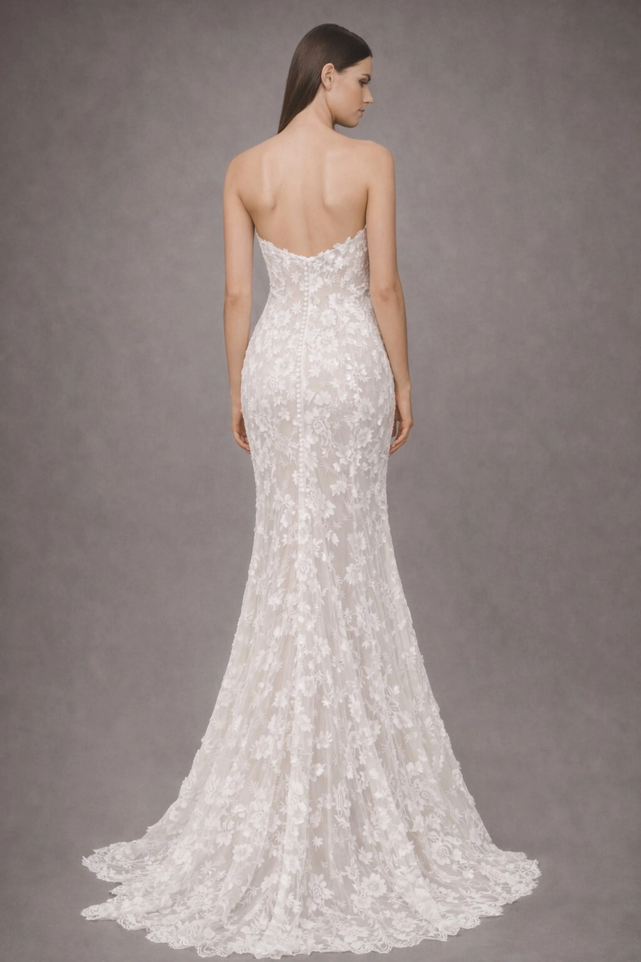 Strapless lace mermaid wedding dress with floral appliqué, sheer bodice, and long train back view