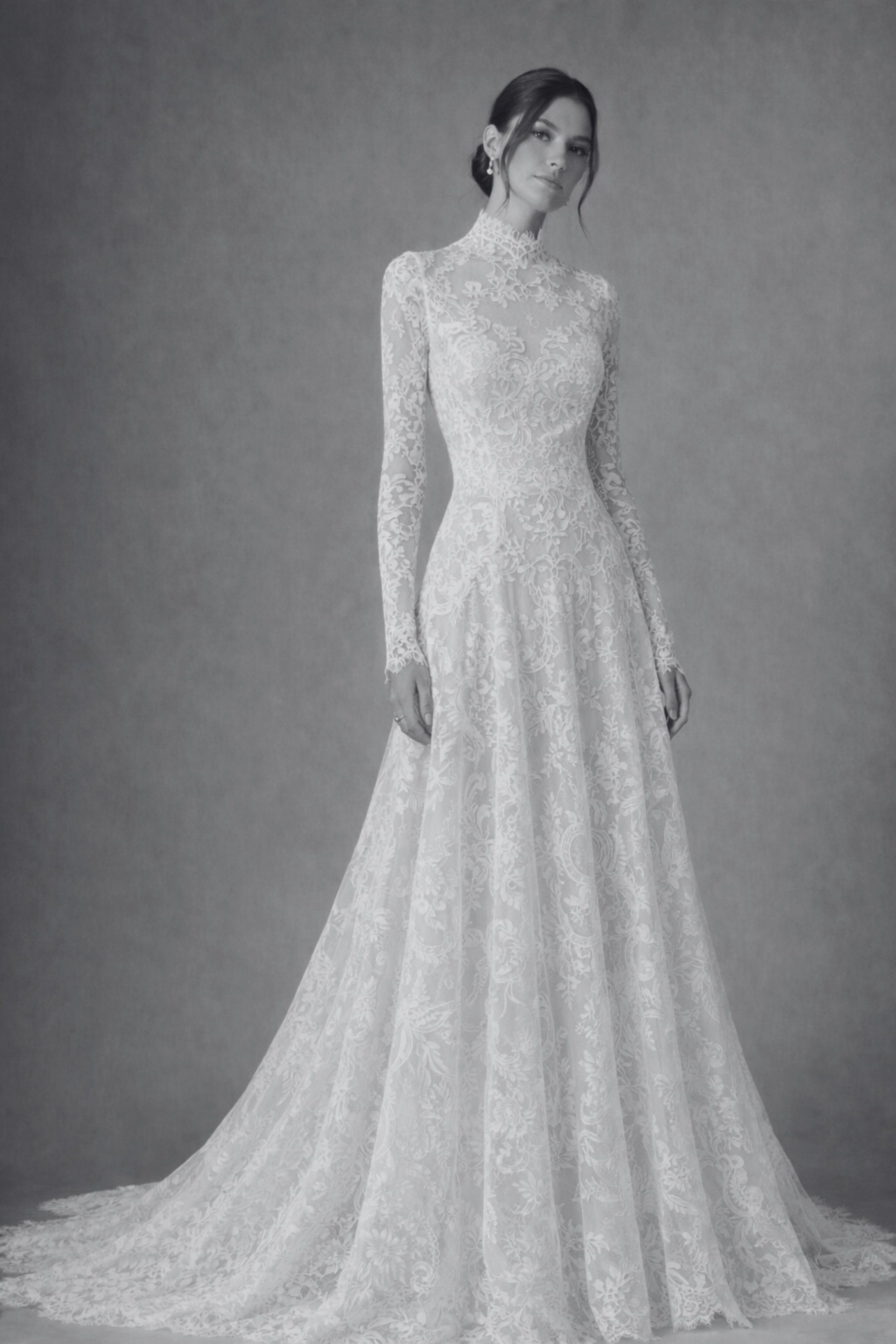Long-sleeve lace wedding dress with high neckline, button-back bodice, and flowing A-line skirt