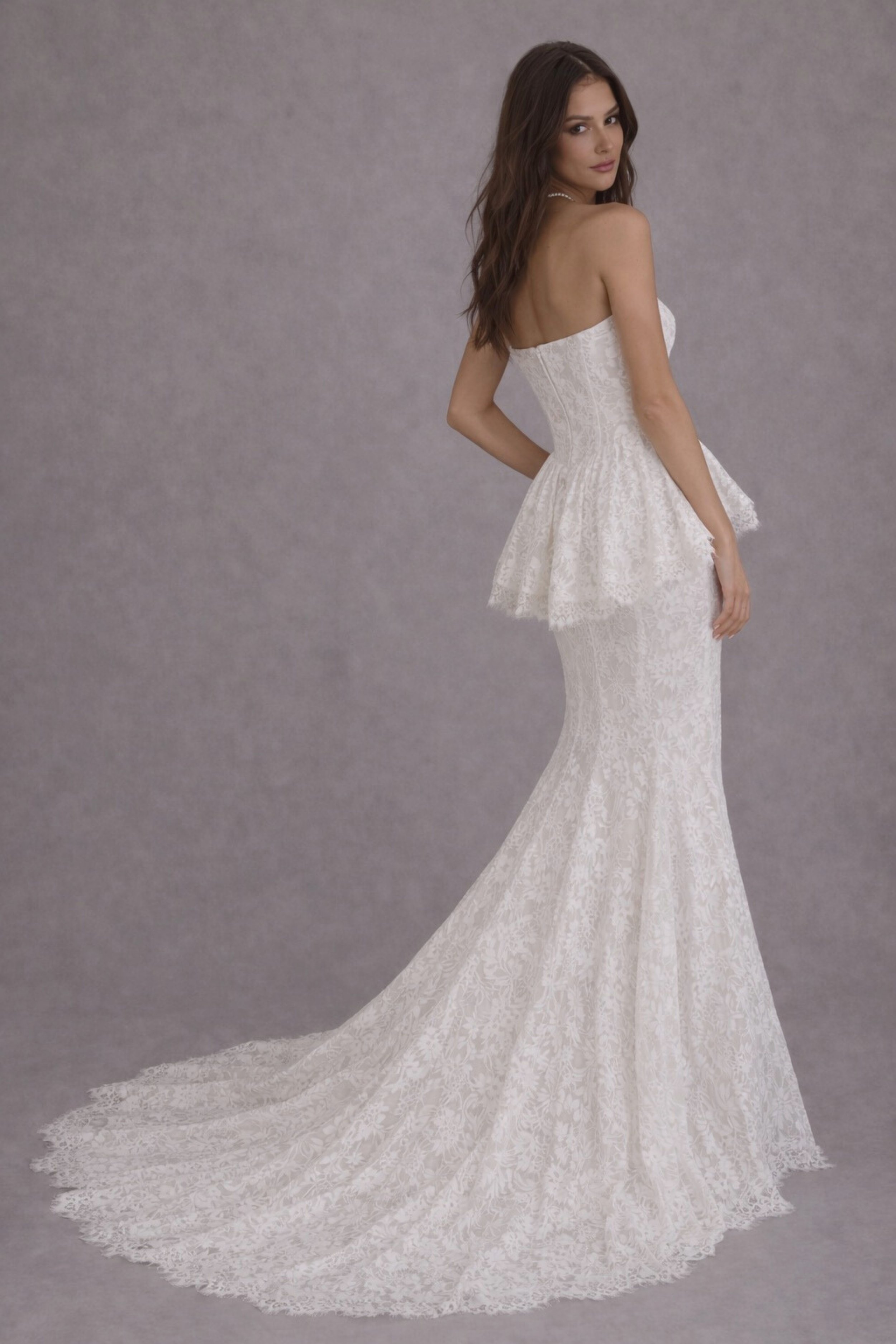 Strapless lace mermaid wedding dress with peplum waist and flowing train, elegant bridal gown