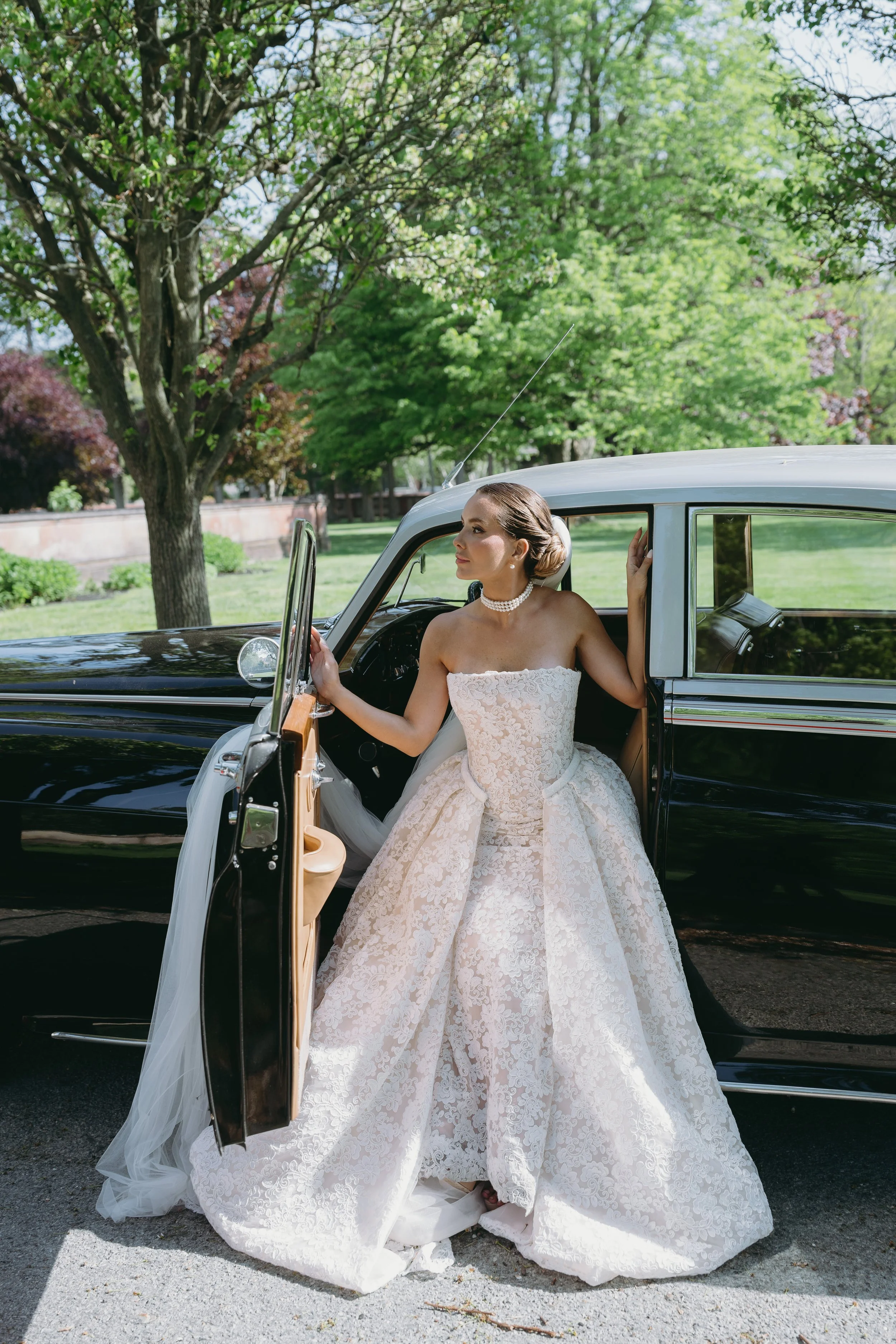 Convertible strapless lace wedding dress with a fitted sheath silhouette, detachable A-line overskirt, floral lace, and cathedral train.