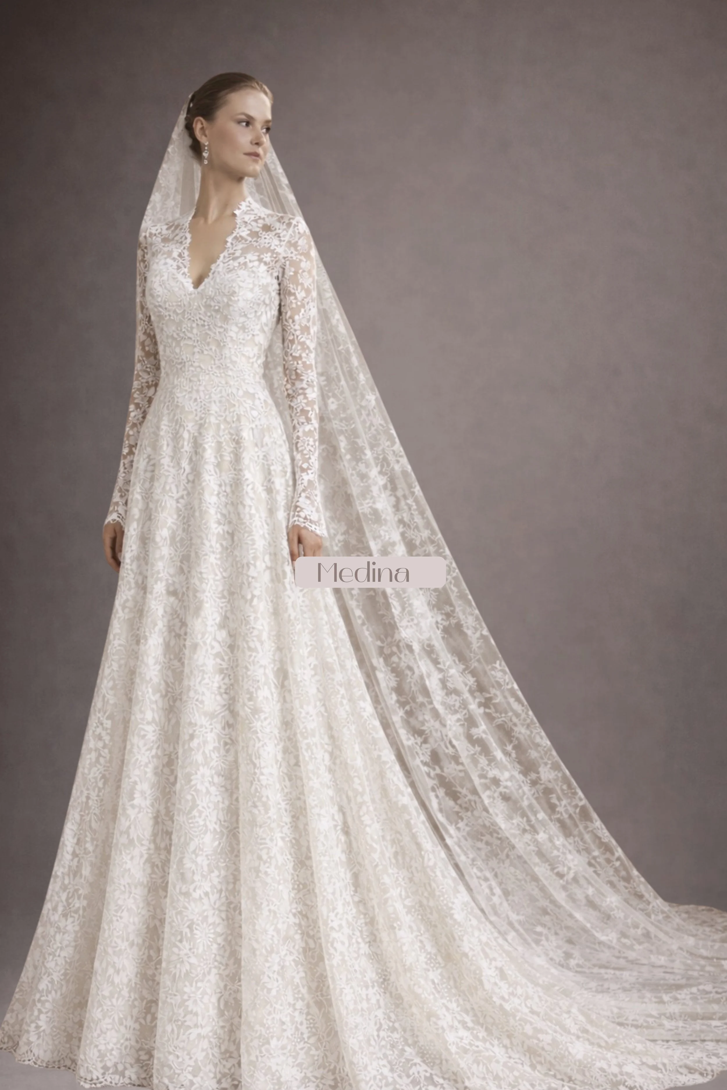 Long sleeve lace wedding dress with V-neckline, fitted bodice, flowing A-line skirt, and lace veil