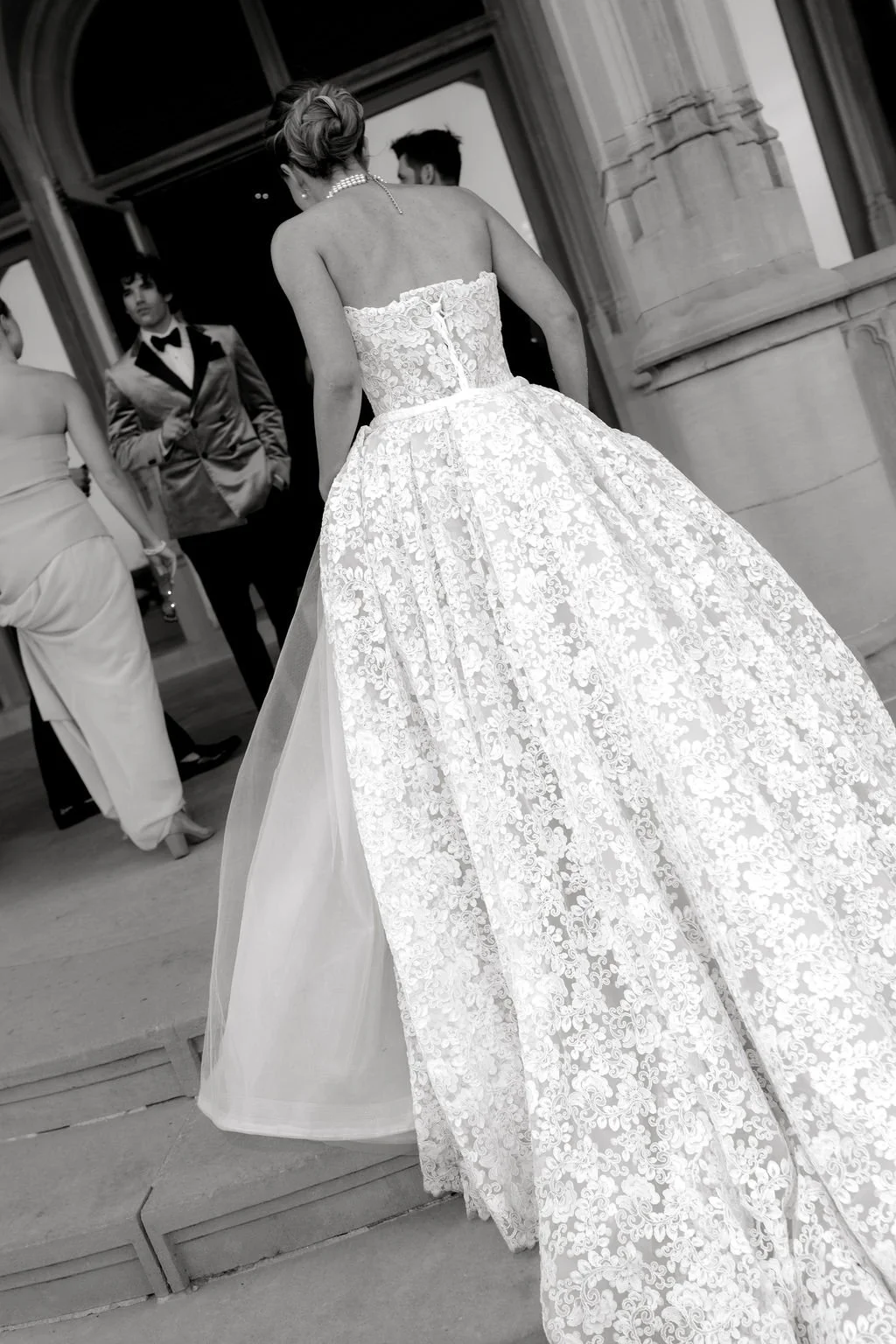 Convertible strapless lace wedding dress with a fitted sheath silhouette, detachable A-line overskirt, floral lace, and cathedral train.