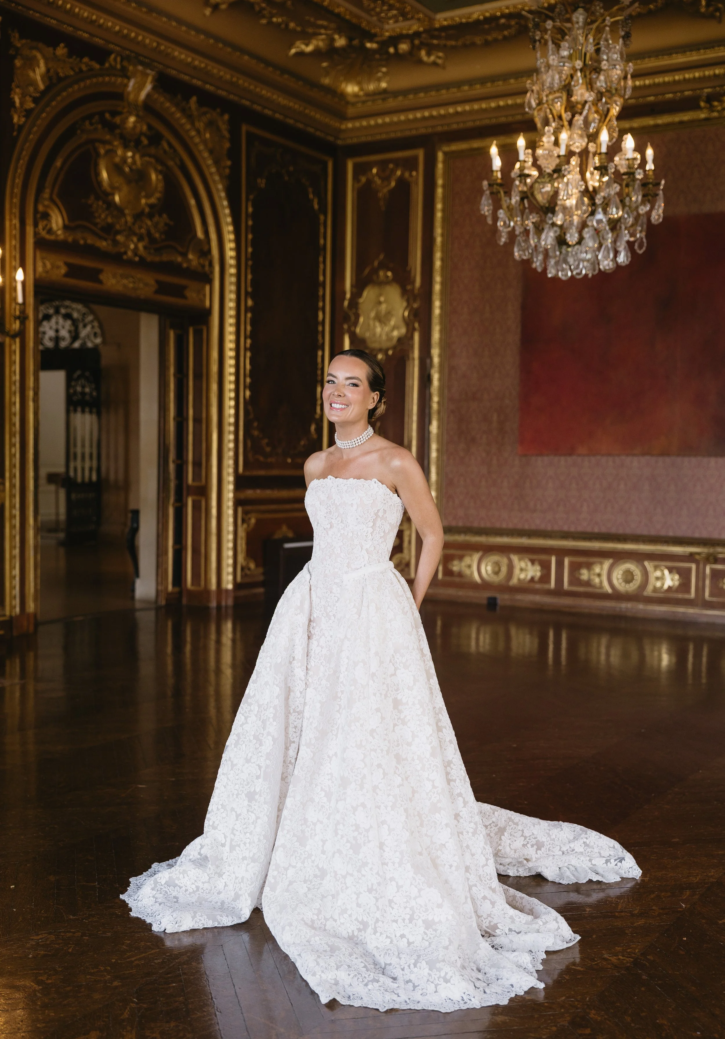 Convertible strapless lace wedding dress with a fitted sheath silhouette, detachable A-line overskirt, floral lace, and cathedral train.