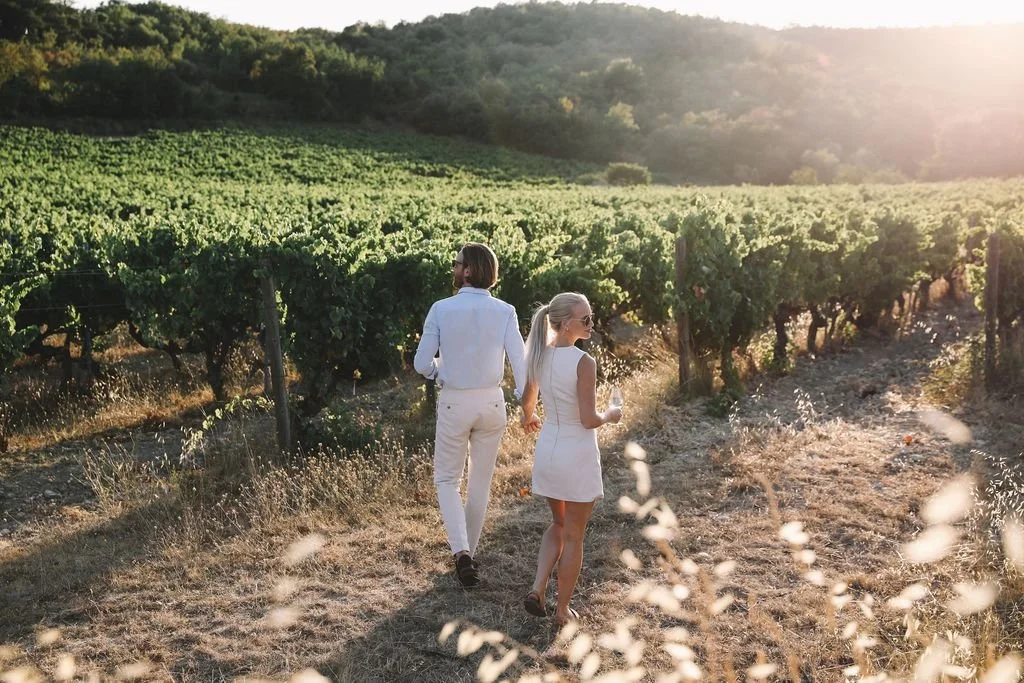 On a Heritage Farmland tour experience, a man and a woman walking through a vineyard during sunset.