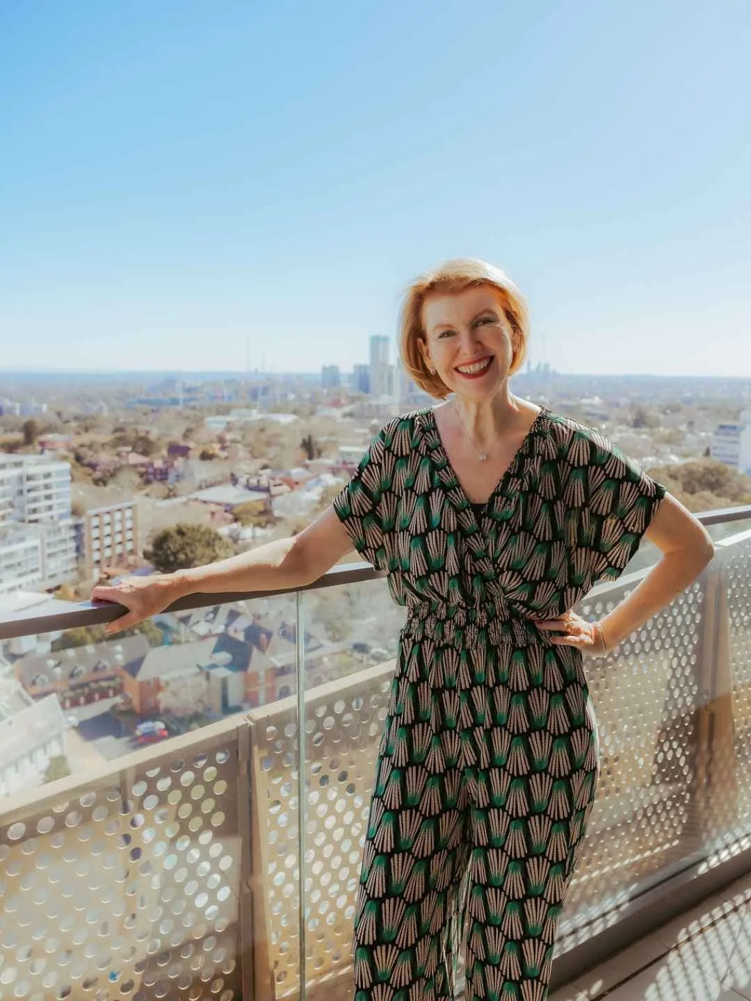 Kate smiling on a balcony with an urban Sydney outlook in the background.