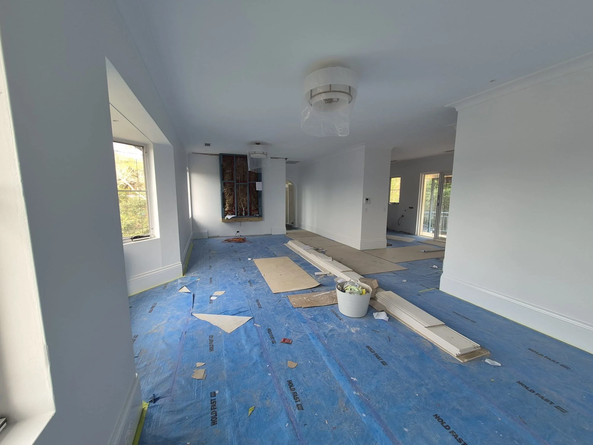 An empty room with protection on the floor, white painted walls and unfinished joinery.