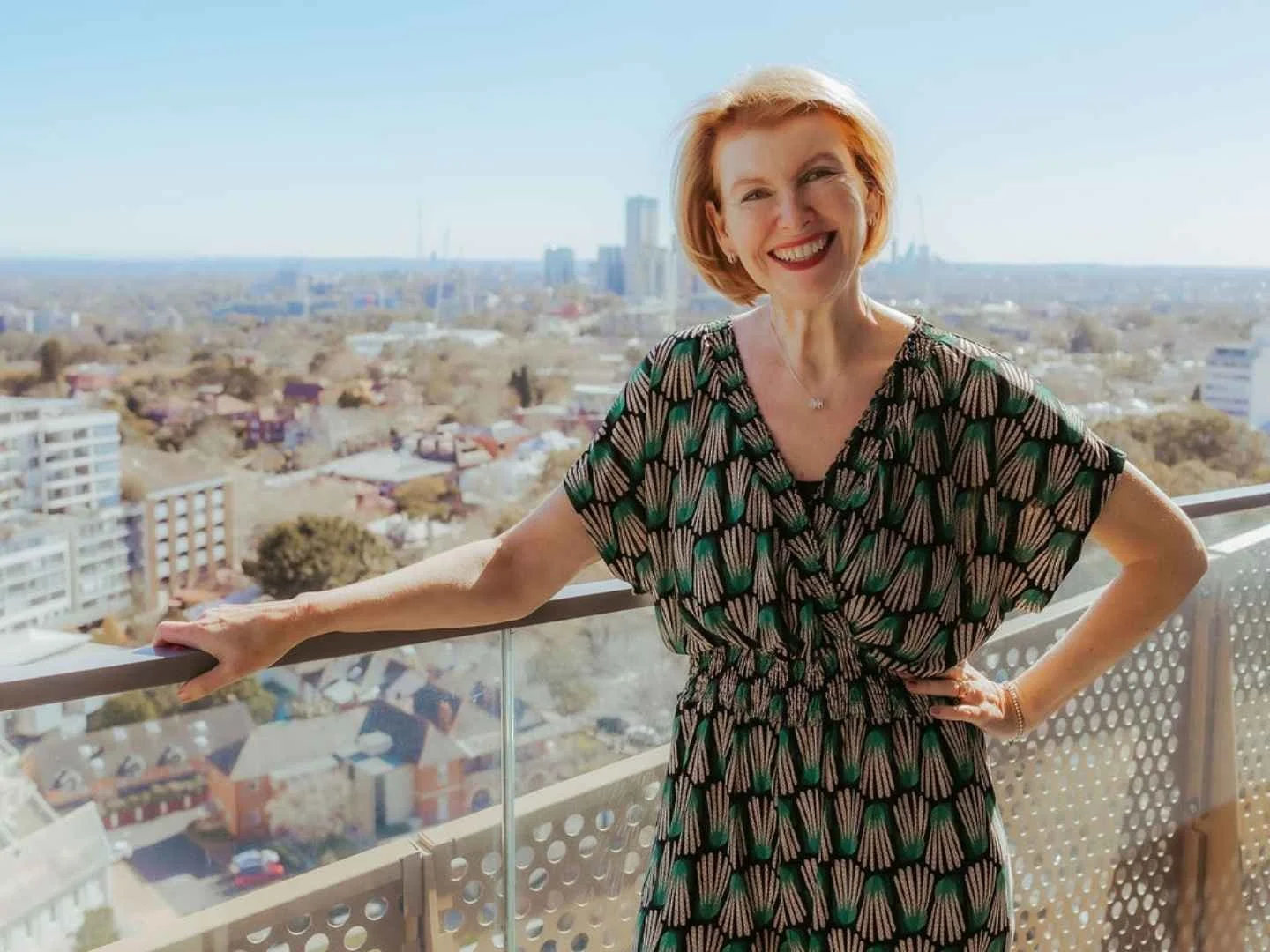 Kate smiling on a balcony with an urban Sydney outlook in the background.