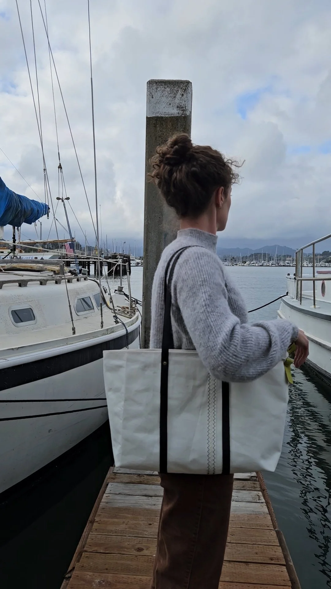 Girl wearing white sail cloth tote bag with black leather handles