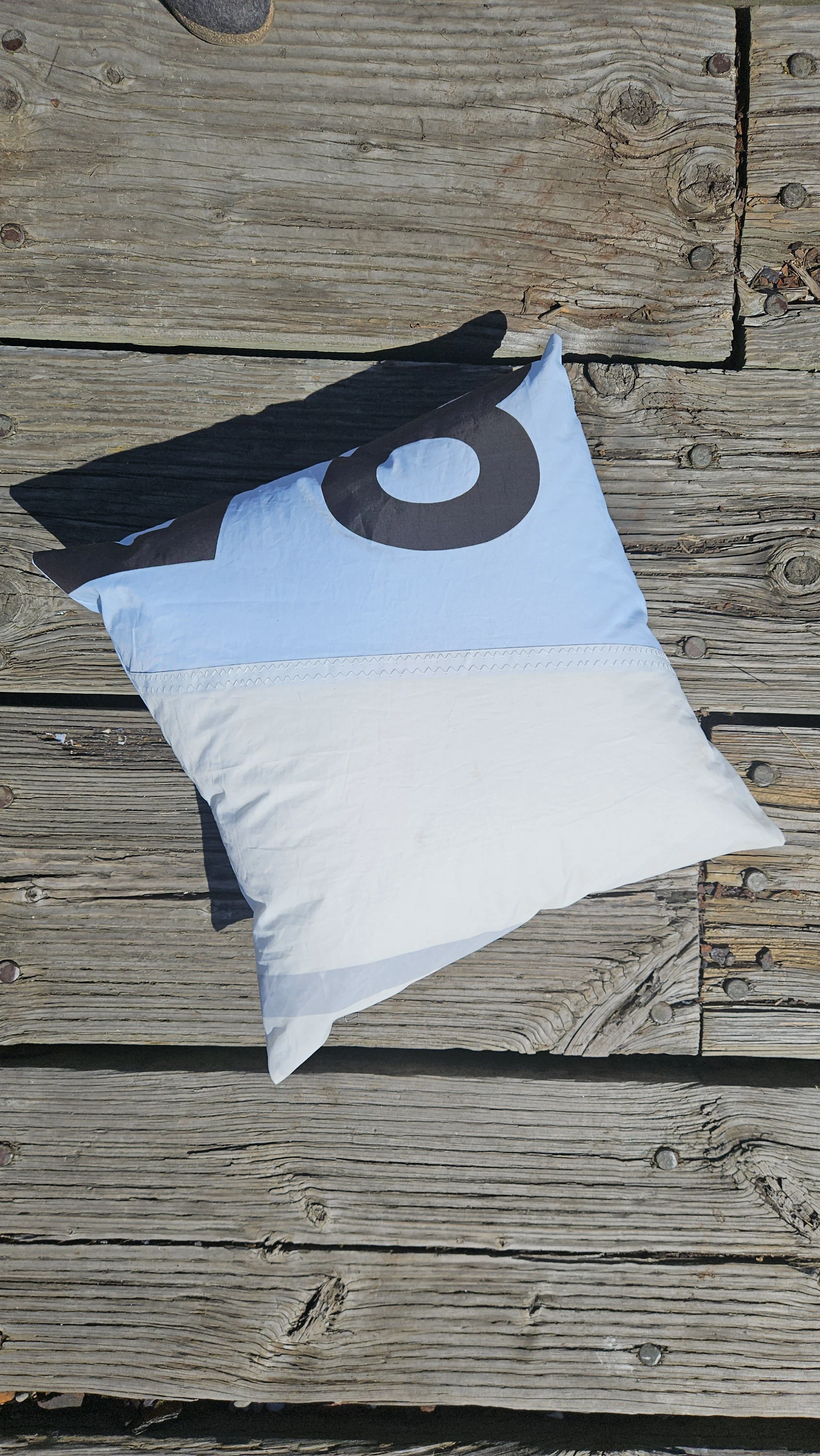 Coastal patio pillow made from reclaimed sailcloth styled for outdoor living