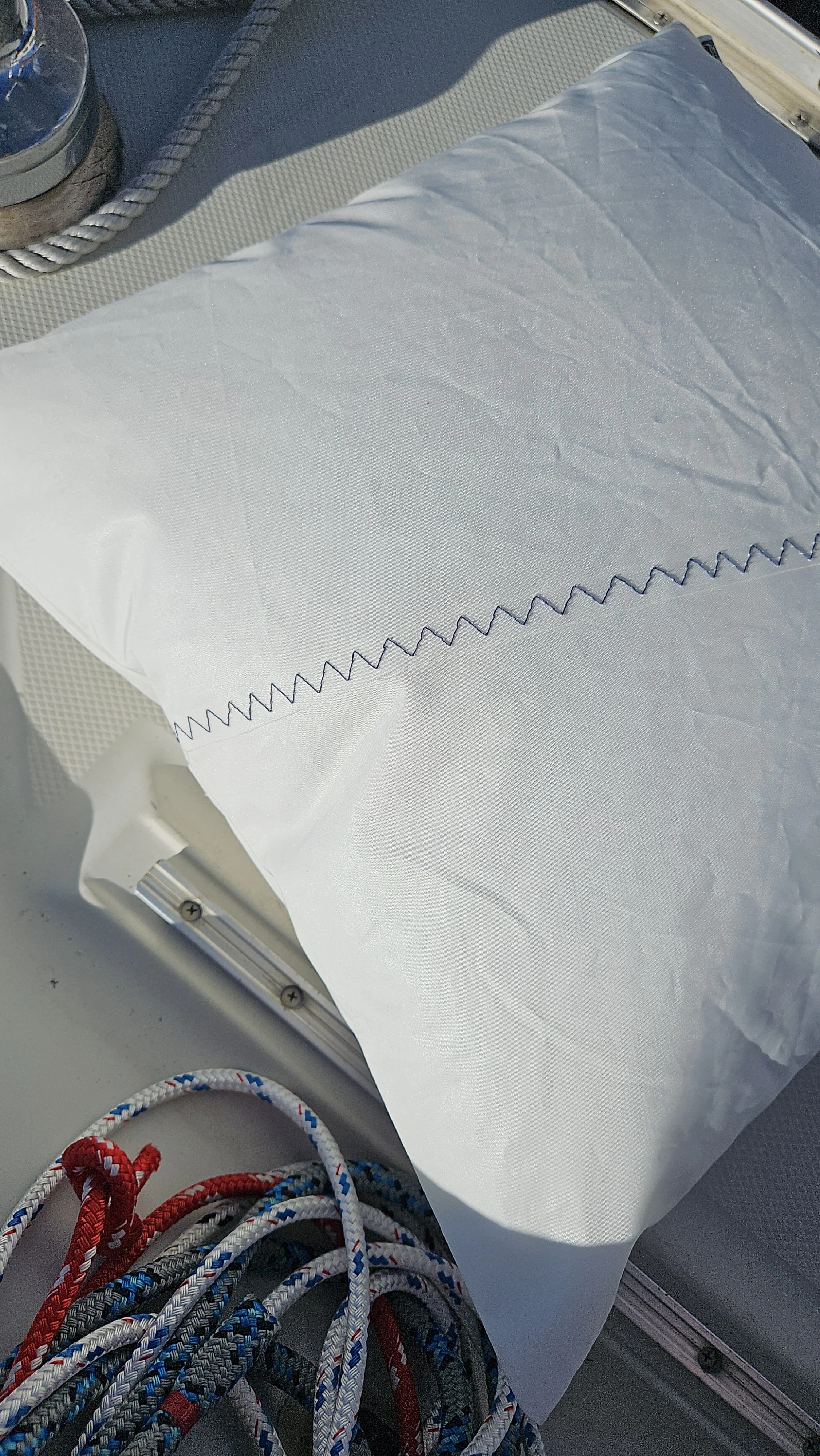 Blue zigzag stitching on white upcycled sailcloth pillow