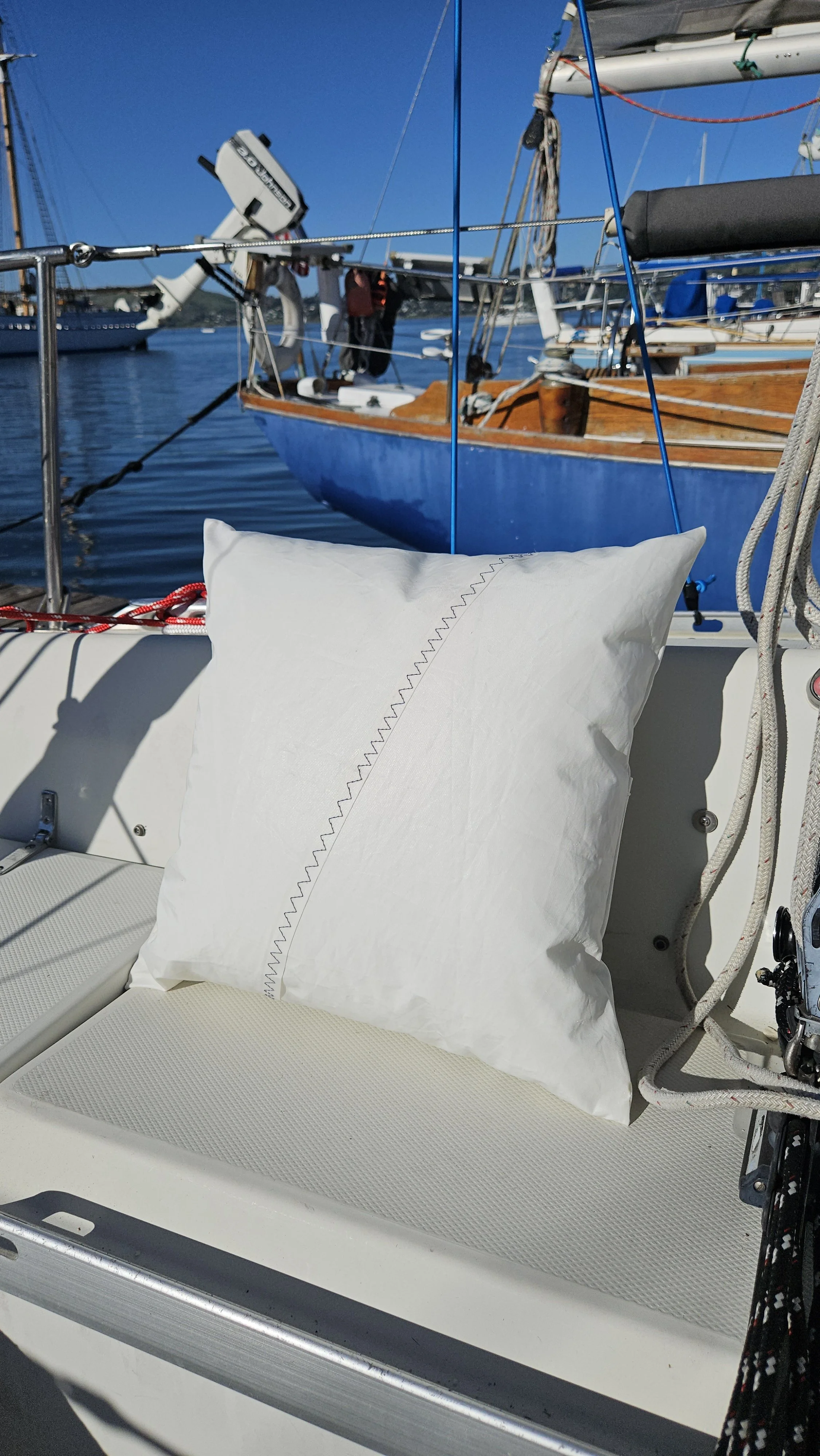 Upcycled sailcloth outdoor pillow made from reclaimed white sailcloth with nautical stitching, designed for coastal patio decor