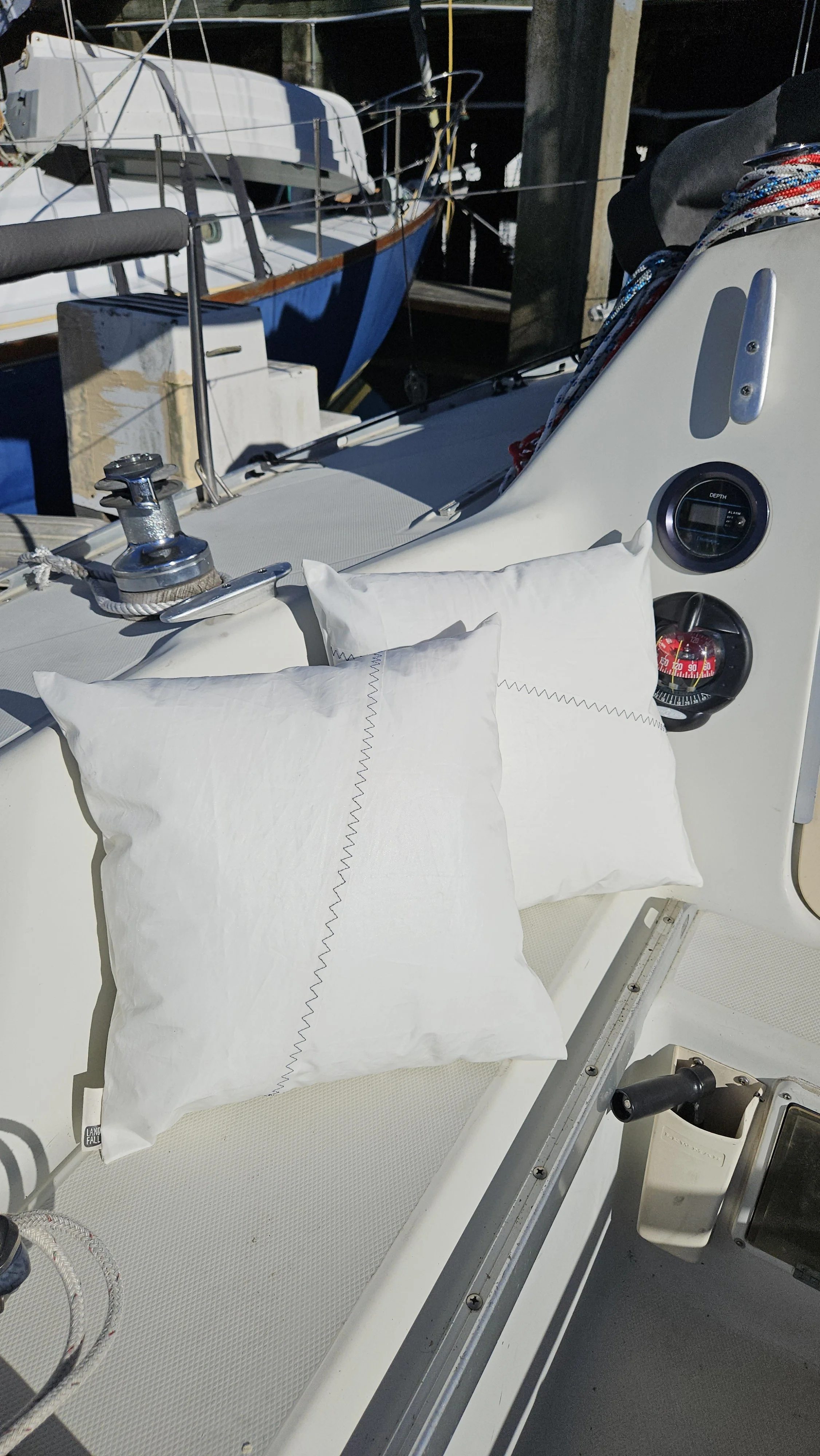 Upcycled sailcloth outdoor pillows made from reclaimed white sailcloth with nautical stitching, designed for coastal patio decor