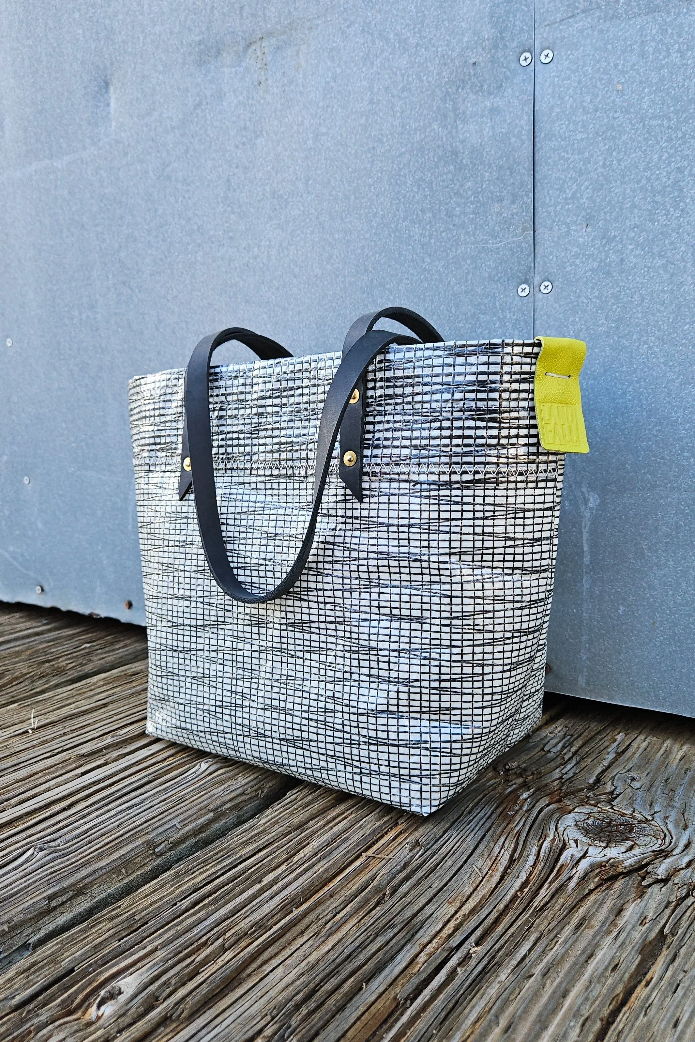 Black carbon sailcloth tote bag with black leather handles sitting on dock