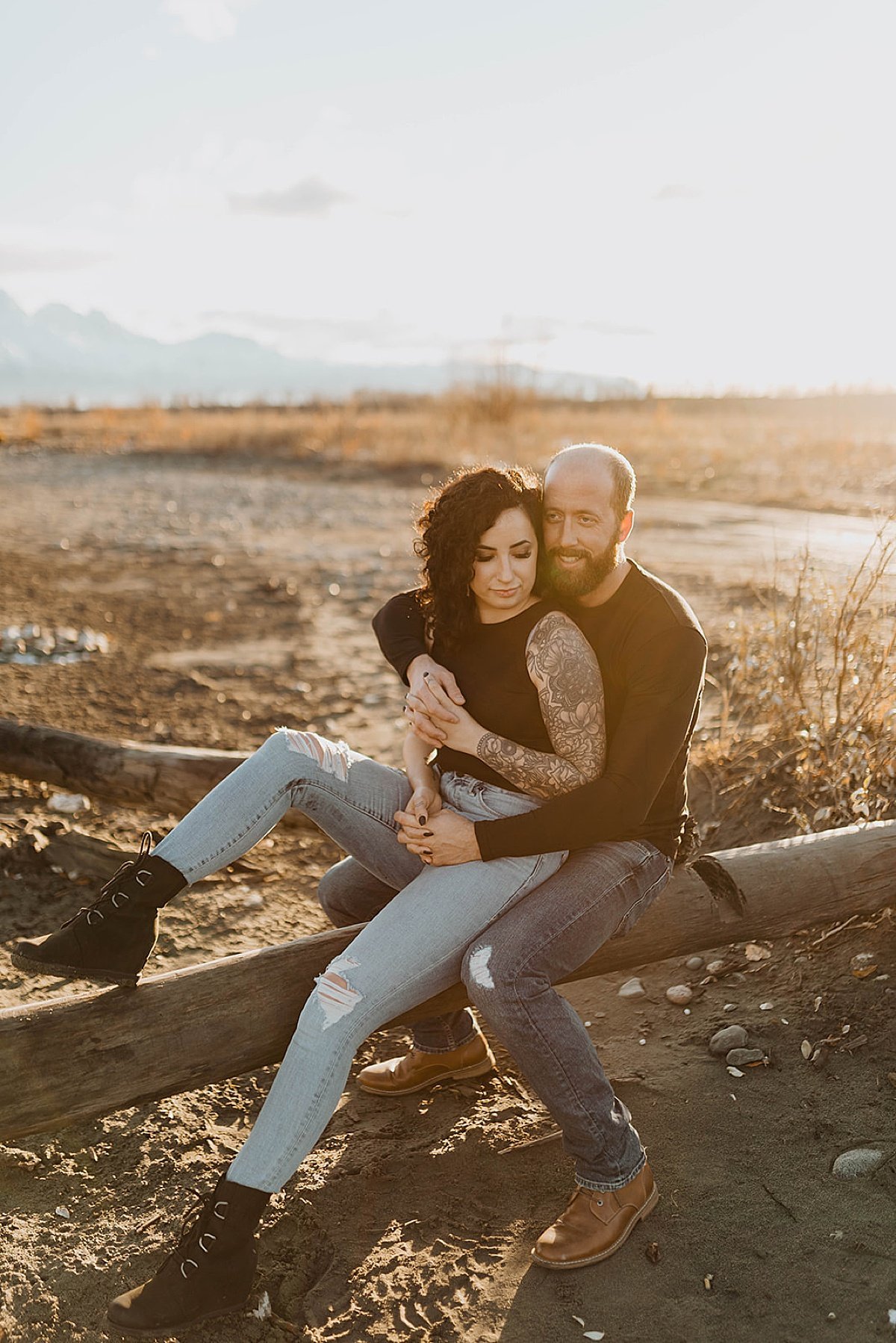  Hip outdoorsy couple with artsy tattoos pose on fallen log in engagement shoot by Alaska wedding photographer 