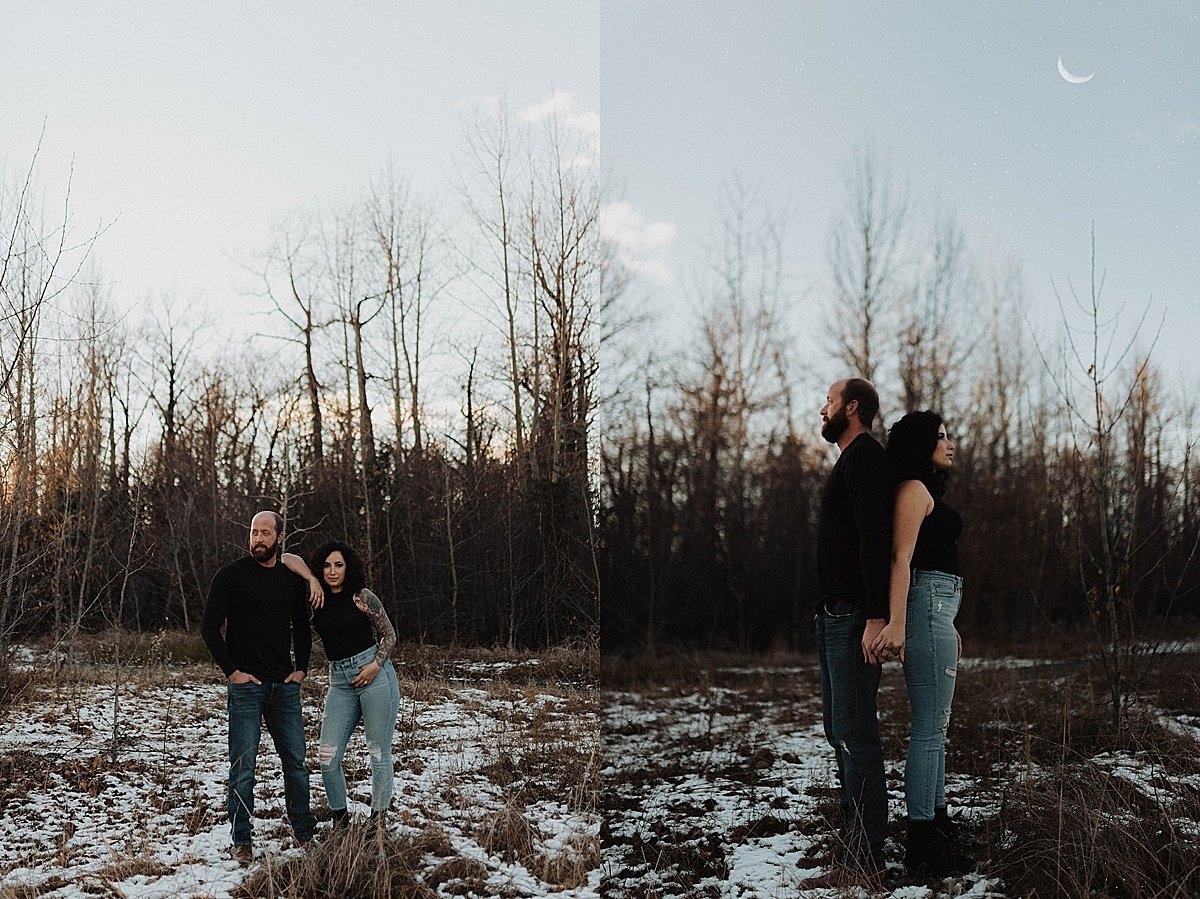  Artsy engaged couple stand back to back under forest sky with moon above in shoot by Theresa McDonald Photography 