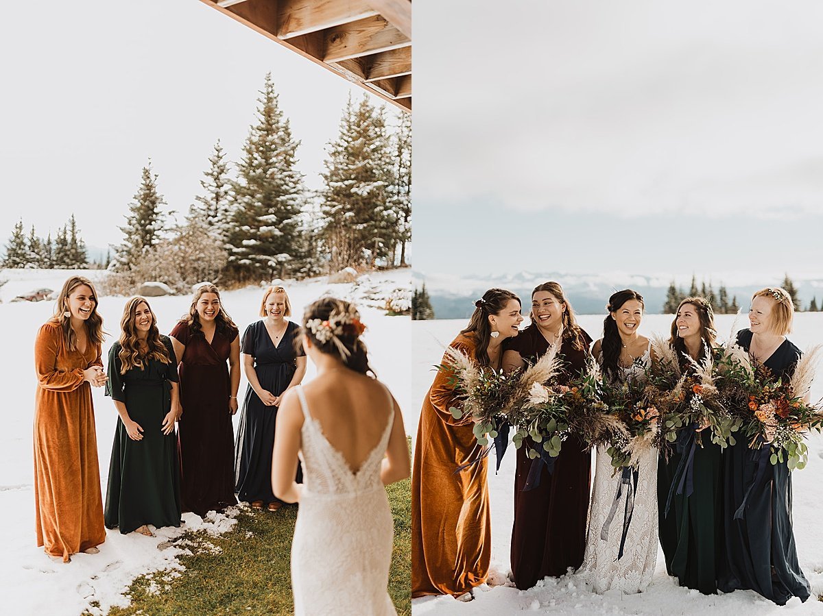  bridal party wearing autumn velvet dresses reacts to bride in white lace gown at snowy fall wedding 