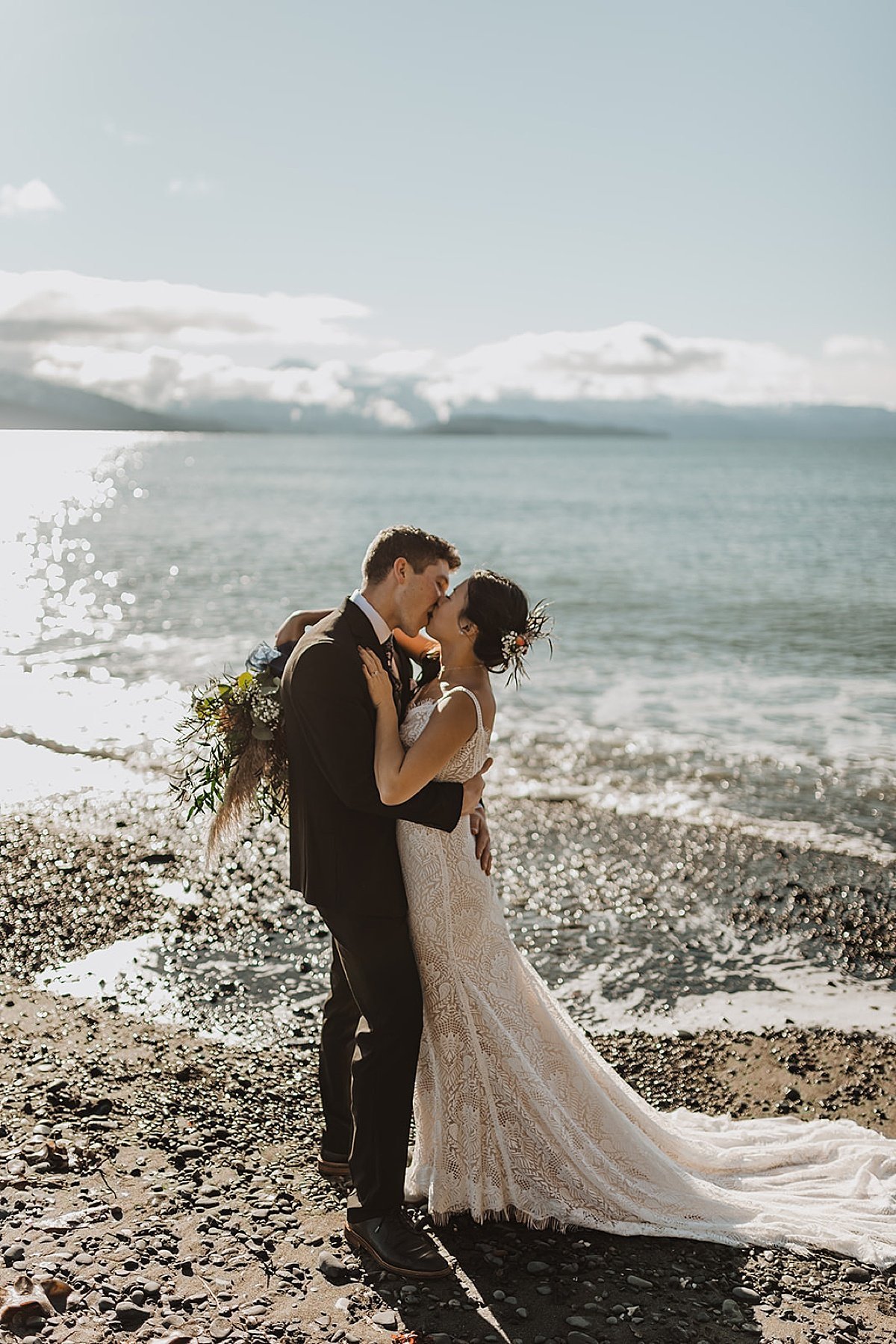  bride with autumn floral bouquet kisses groom on rocky alaska beach during wedding shot by Theresa McDonald Photography 