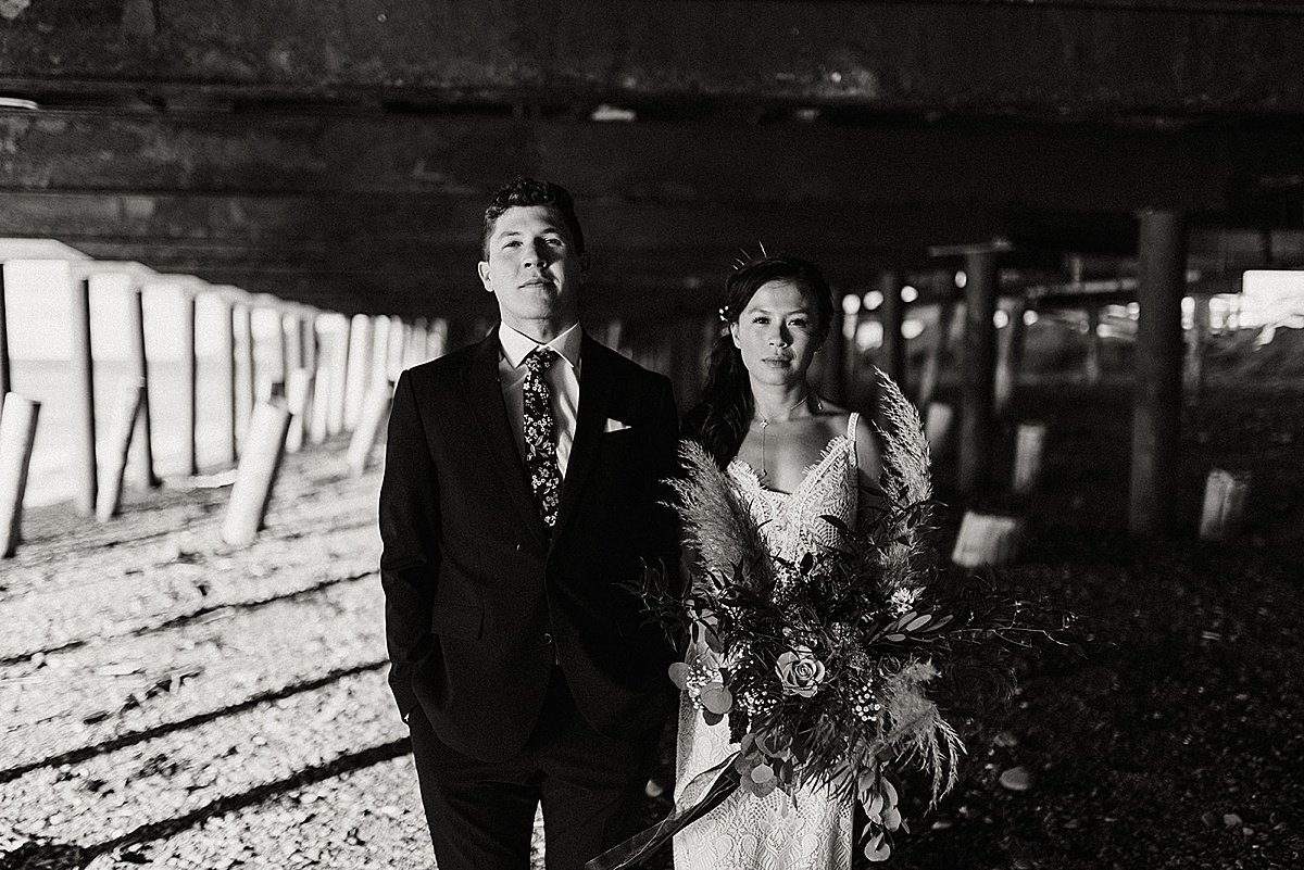  bride and groom pose under pier at lakeside wedding shot by Theresa McDonald Photography 