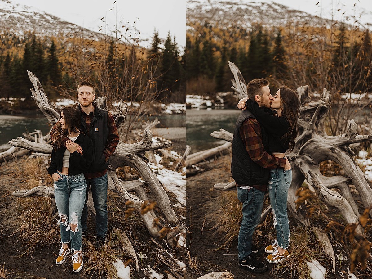  newly engaged couple kiss in front of rugged tree during autumn engagement shoot at alaska mountain  