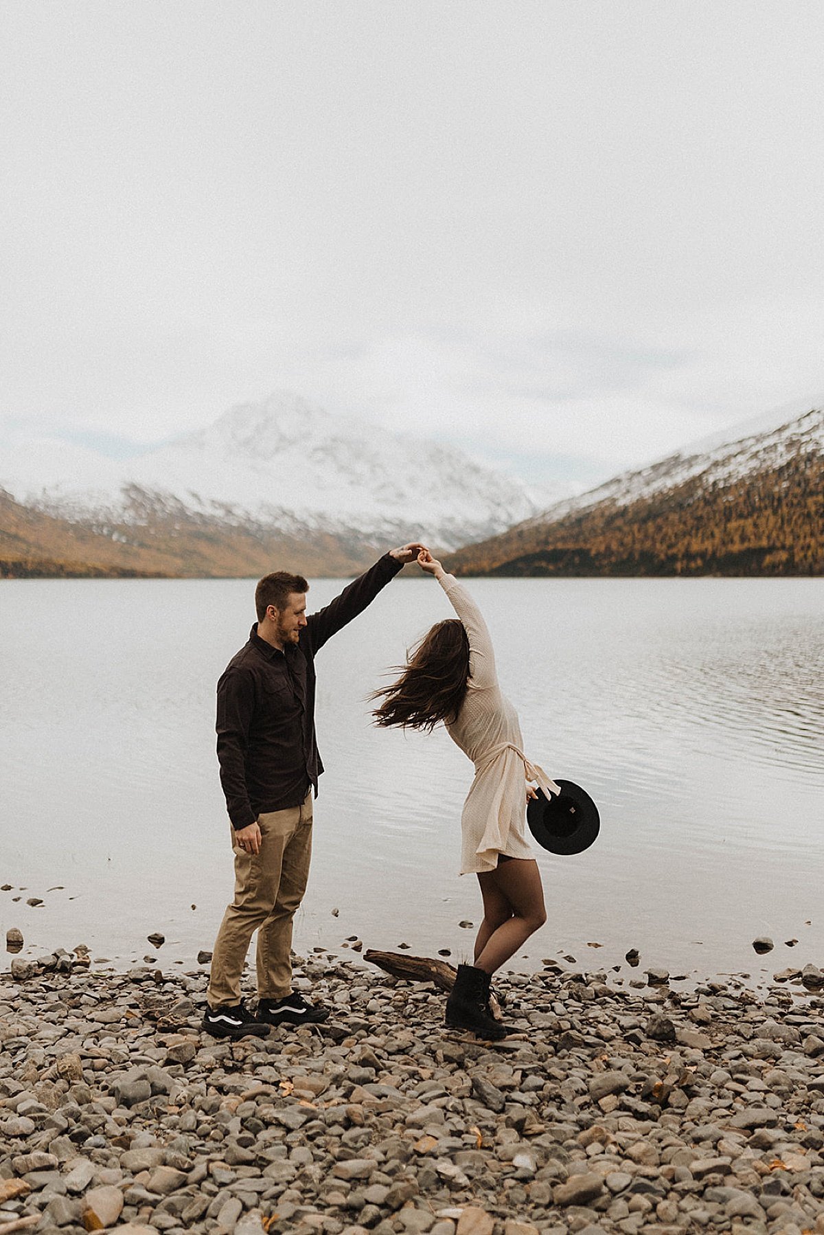  cute engaged couple dance and twirl on rocky beach at mountain lake shoot by theresa mcdonald photography 