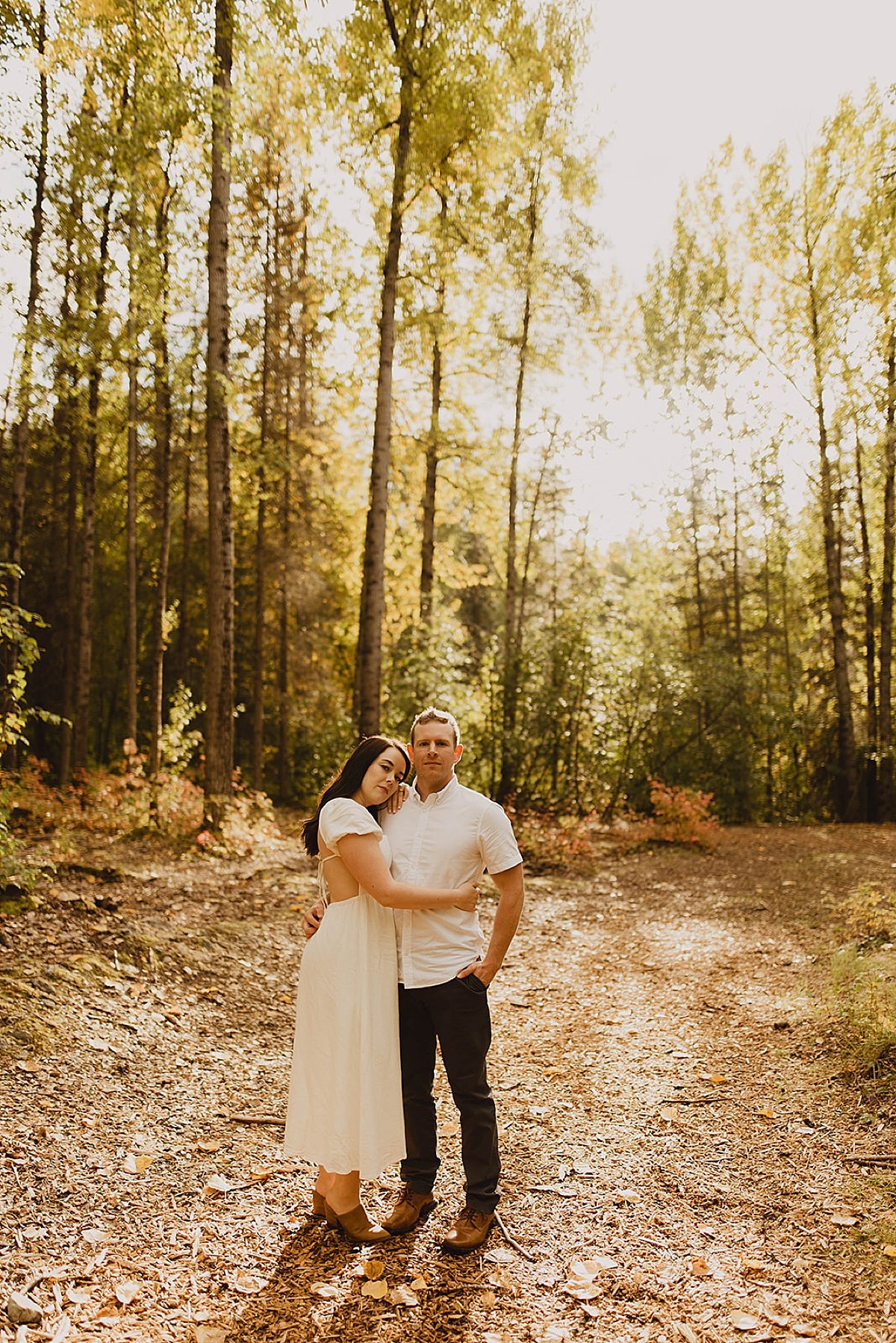  Couple embrace in woodsy engagement shoot during golden hour 