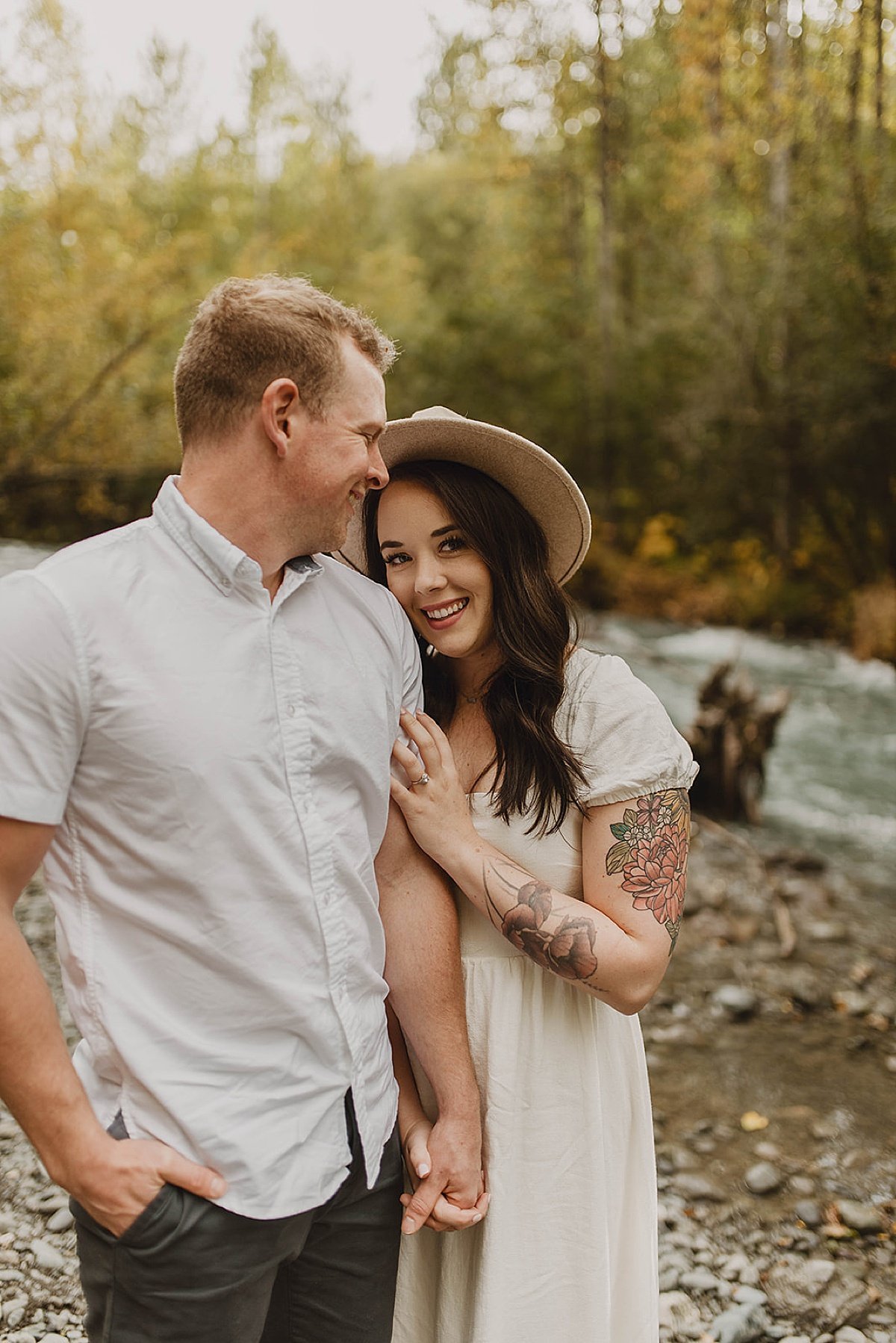  Couples smile in outdoor engagement shoot by riverbank 