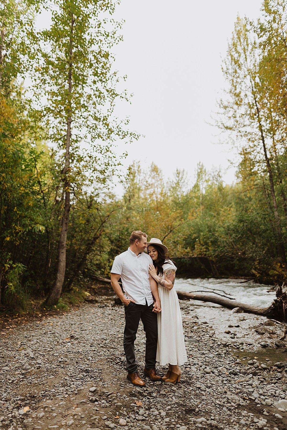  Couple poses lovingly by river in adventure engagement shoot in alaska 