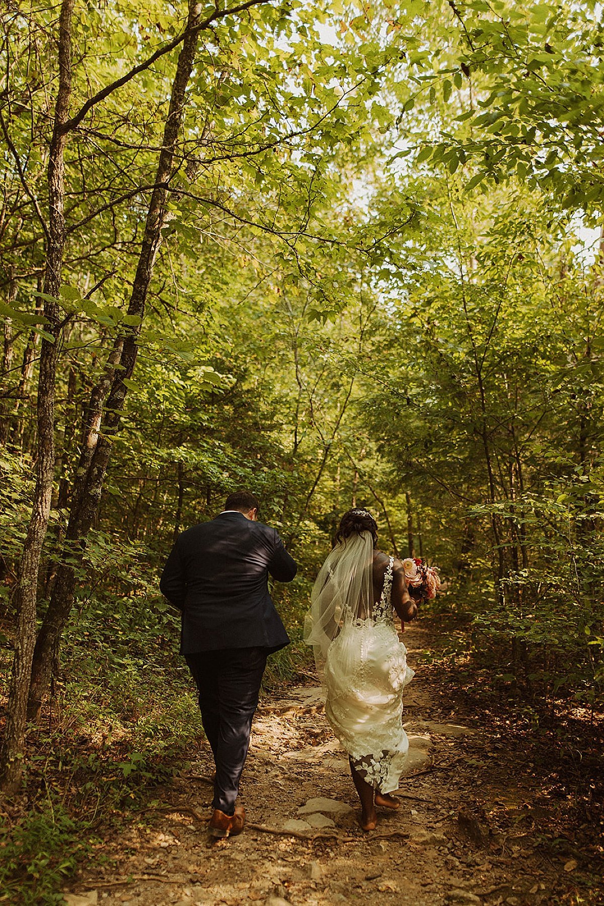  Bride and groom run through sunlit woods after Tennessee wedding ceremony 