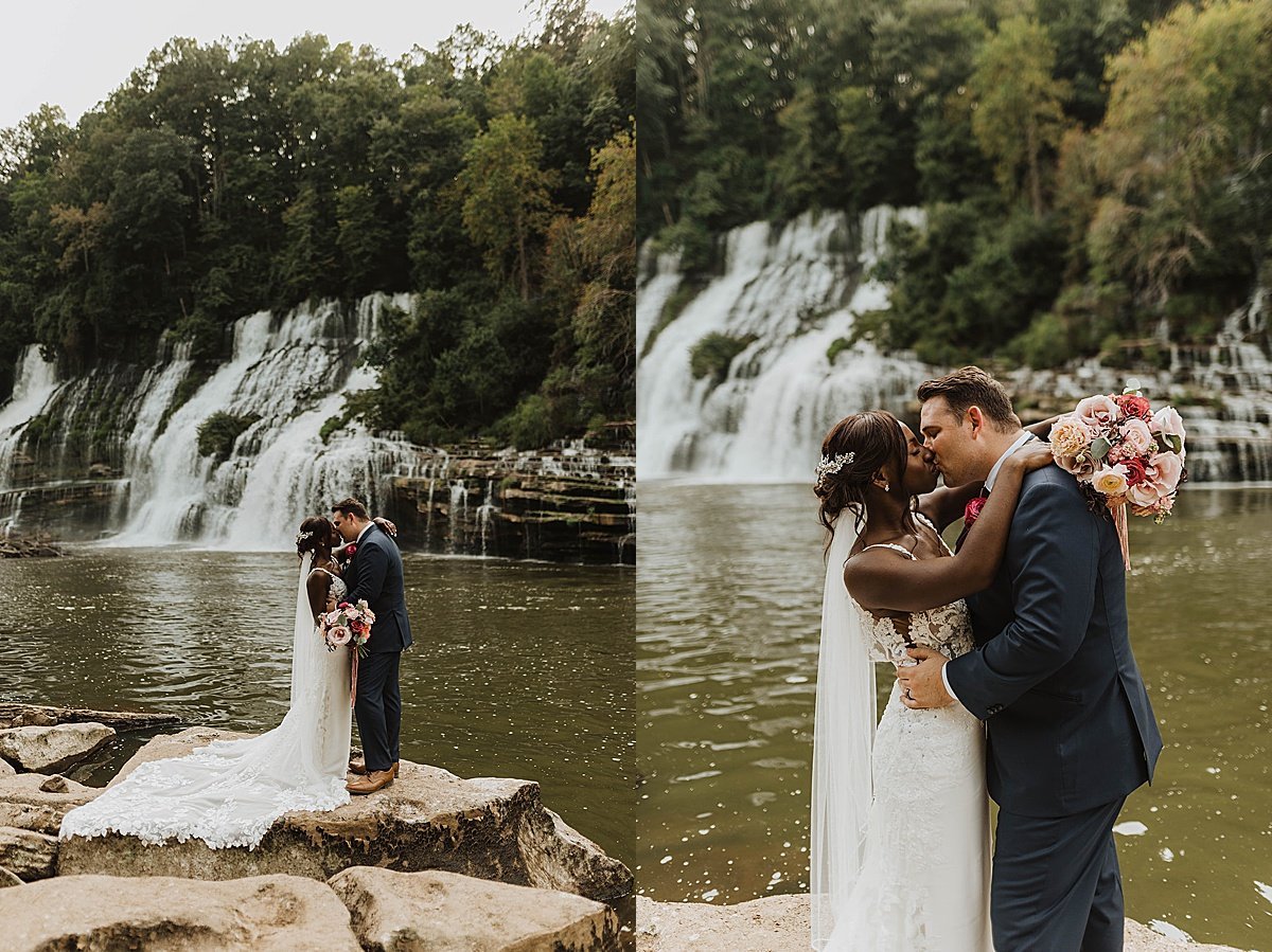  Newlywed bride and groom stop for a kiss in front of waterfall in tuxedo and wedding gown 