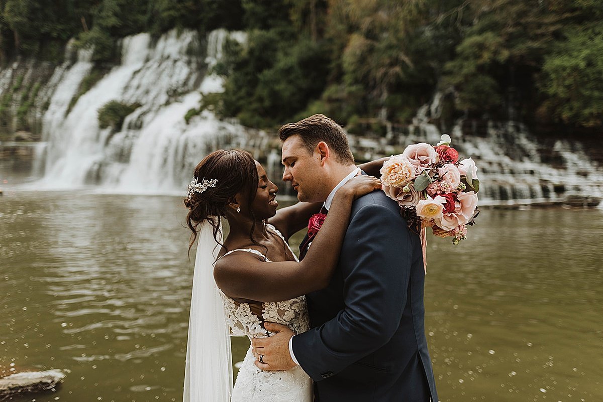  newlyweds kiss in front of waterfall at outdoor wedding by alaska photographer 