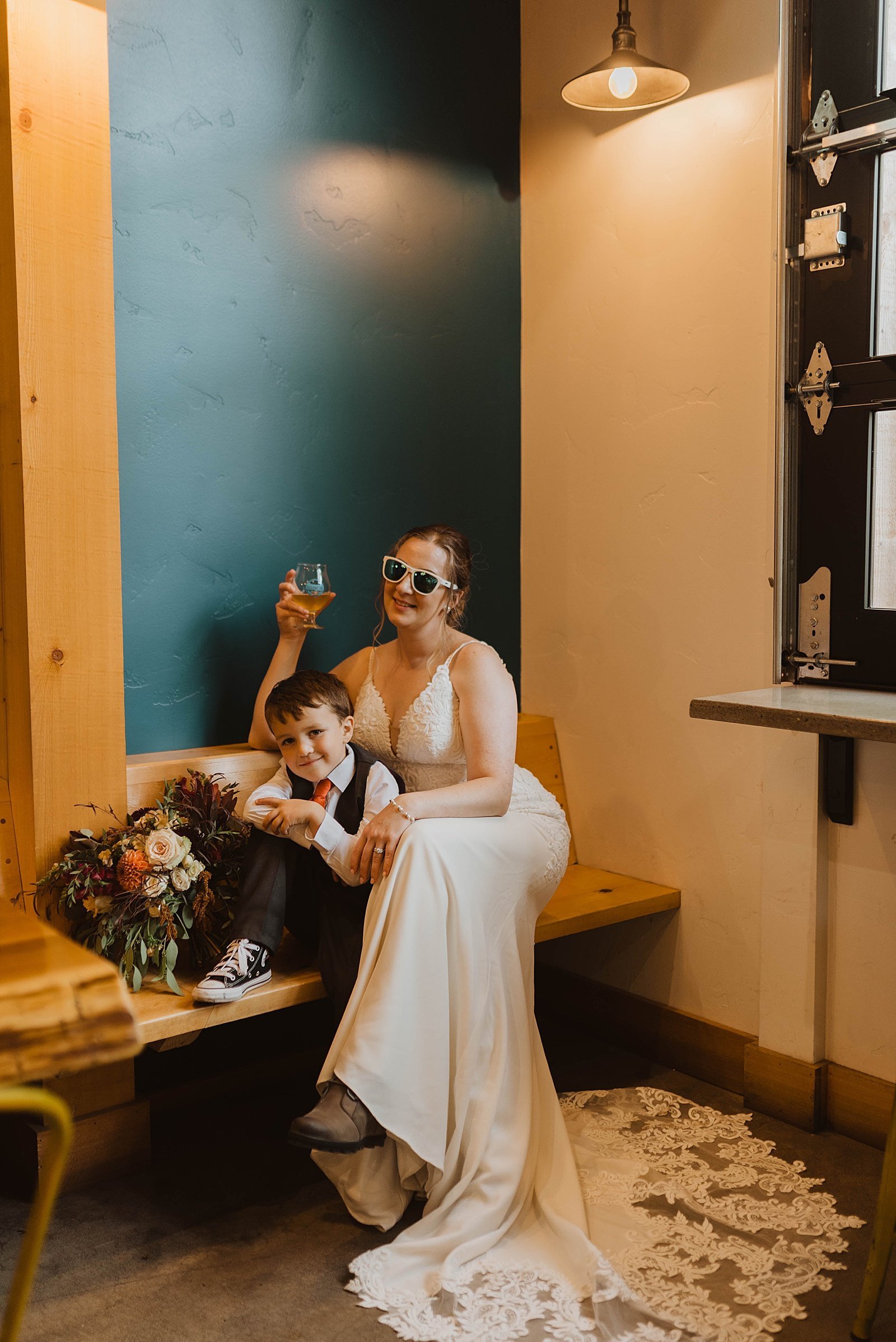  Bride snuggles with her toddler on a bench in a brewery 