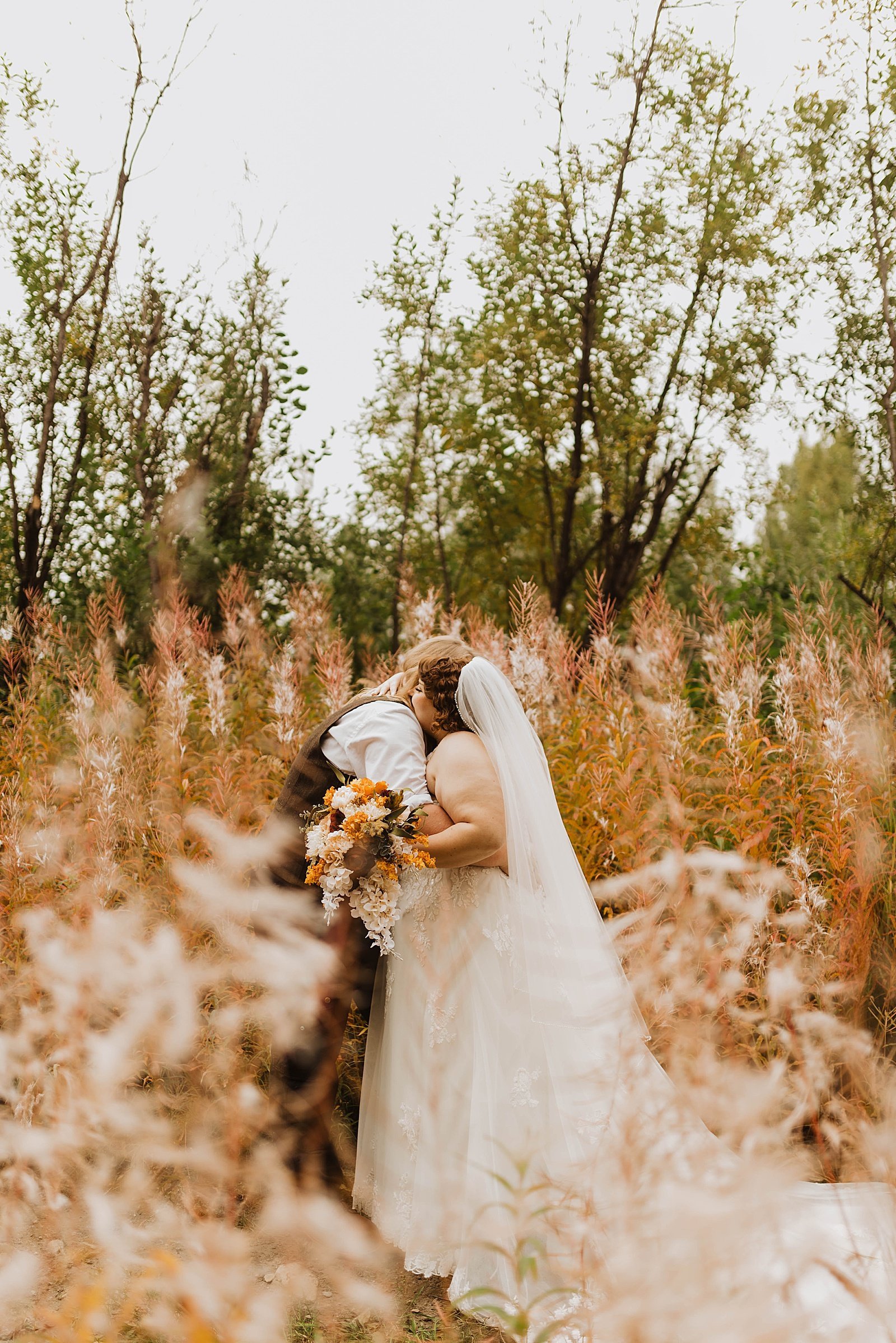  Newlyweds embracing in a field by Alaska wedding photographer, Theresa McDonald 