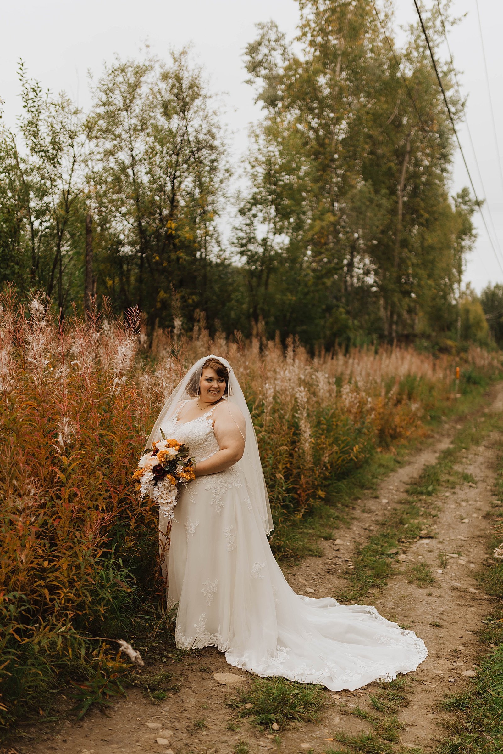  Bride standing in tall grass with her bouquet after her tiny wedding 