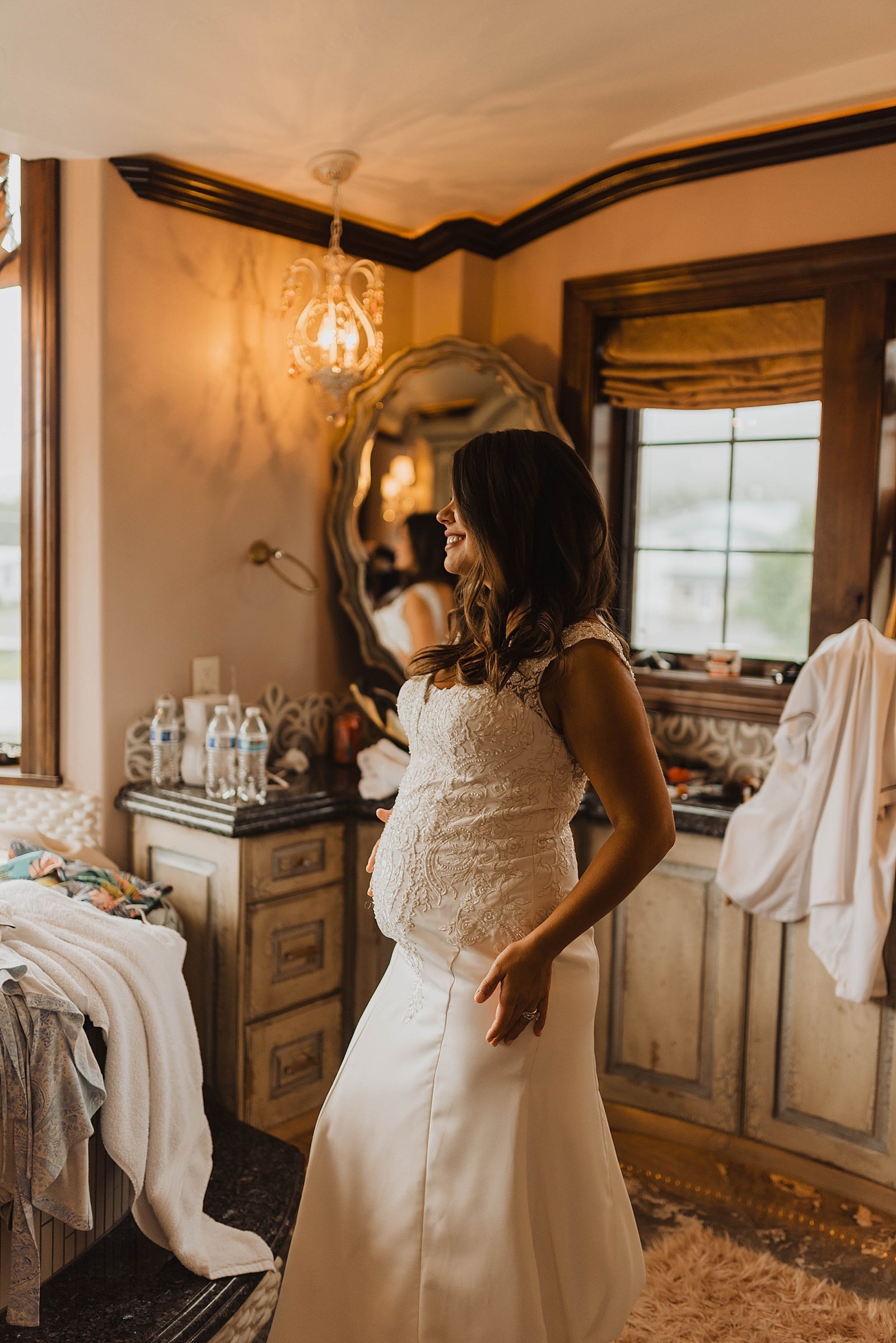  Pregnant bride next to a window in her getting ready room  