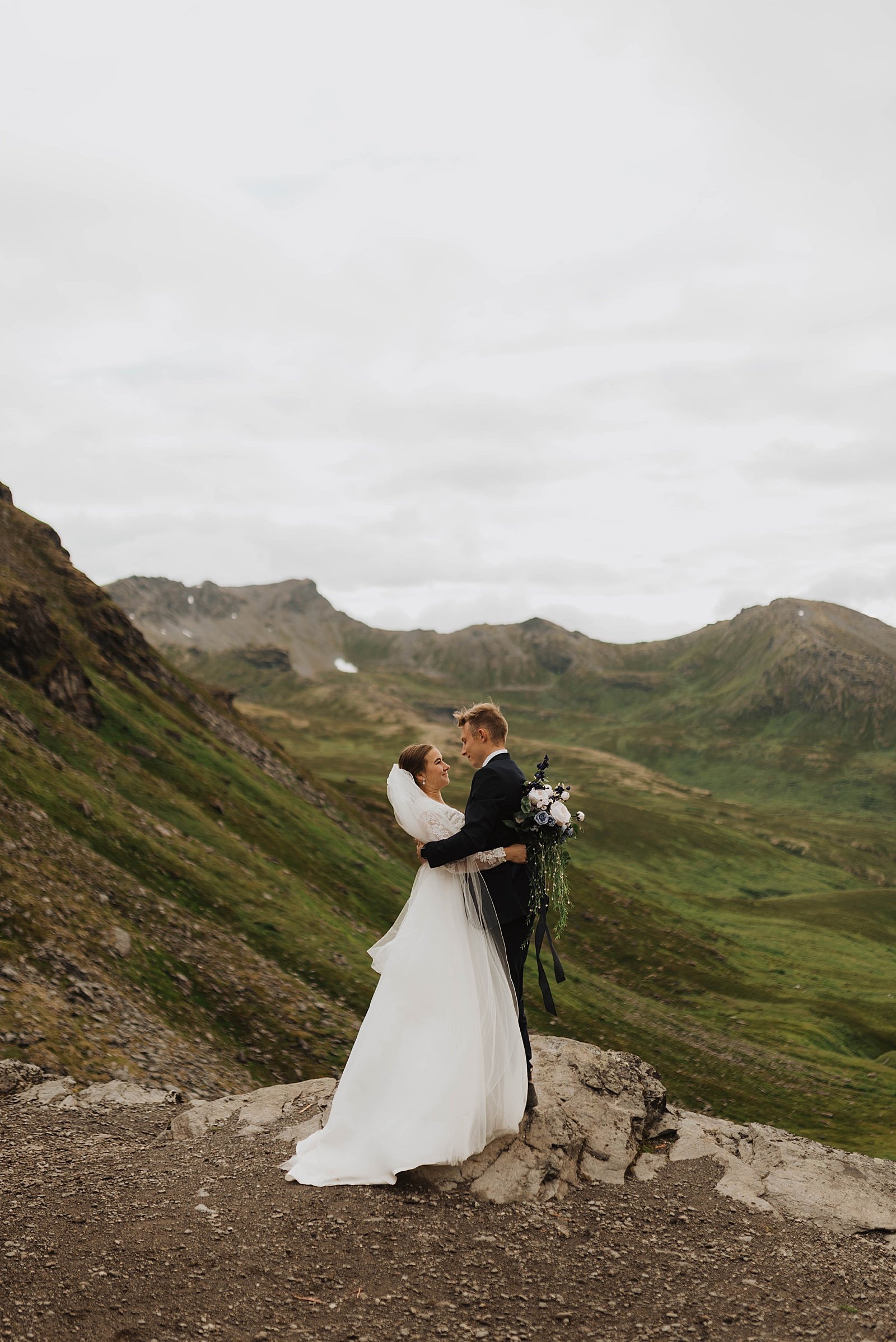  Bride and groom embrace on a mountaintop in Alaska  
