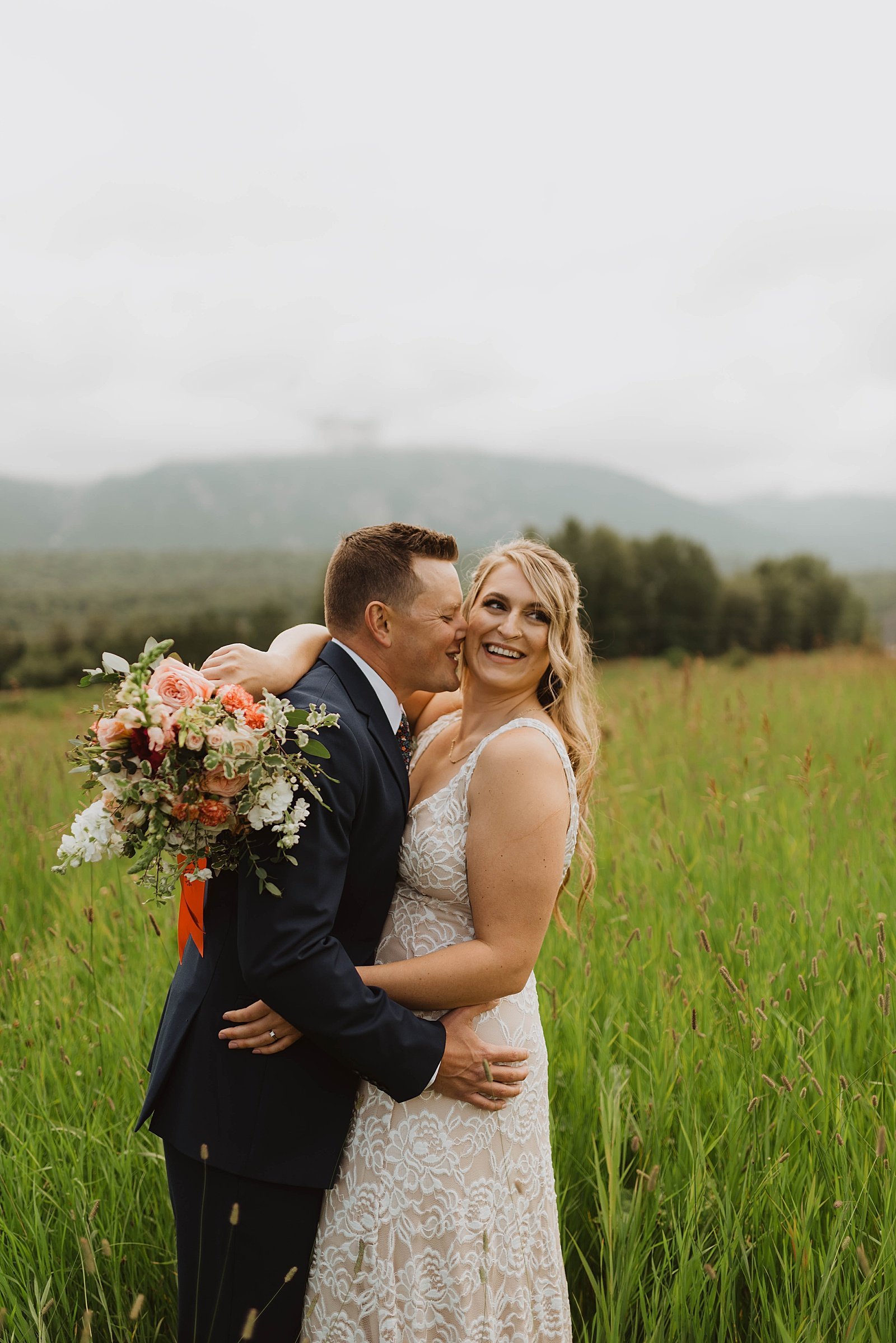  Groom kissing bride’s cheek in a field by Alaska wedding photographer, Theresa McDonald.  