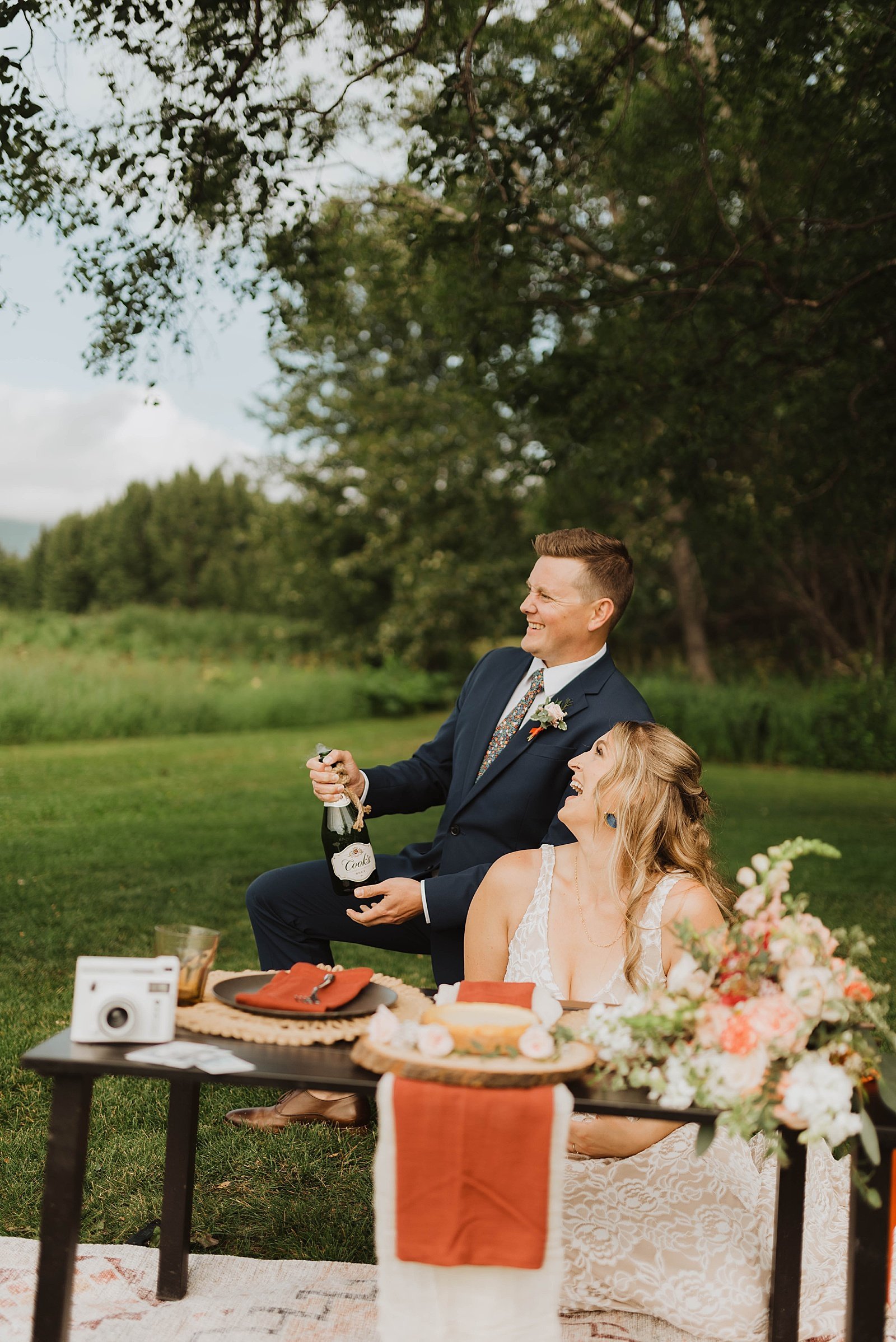  Groom popping champagne at styled wedding picnic for their 10 year anniversary.  