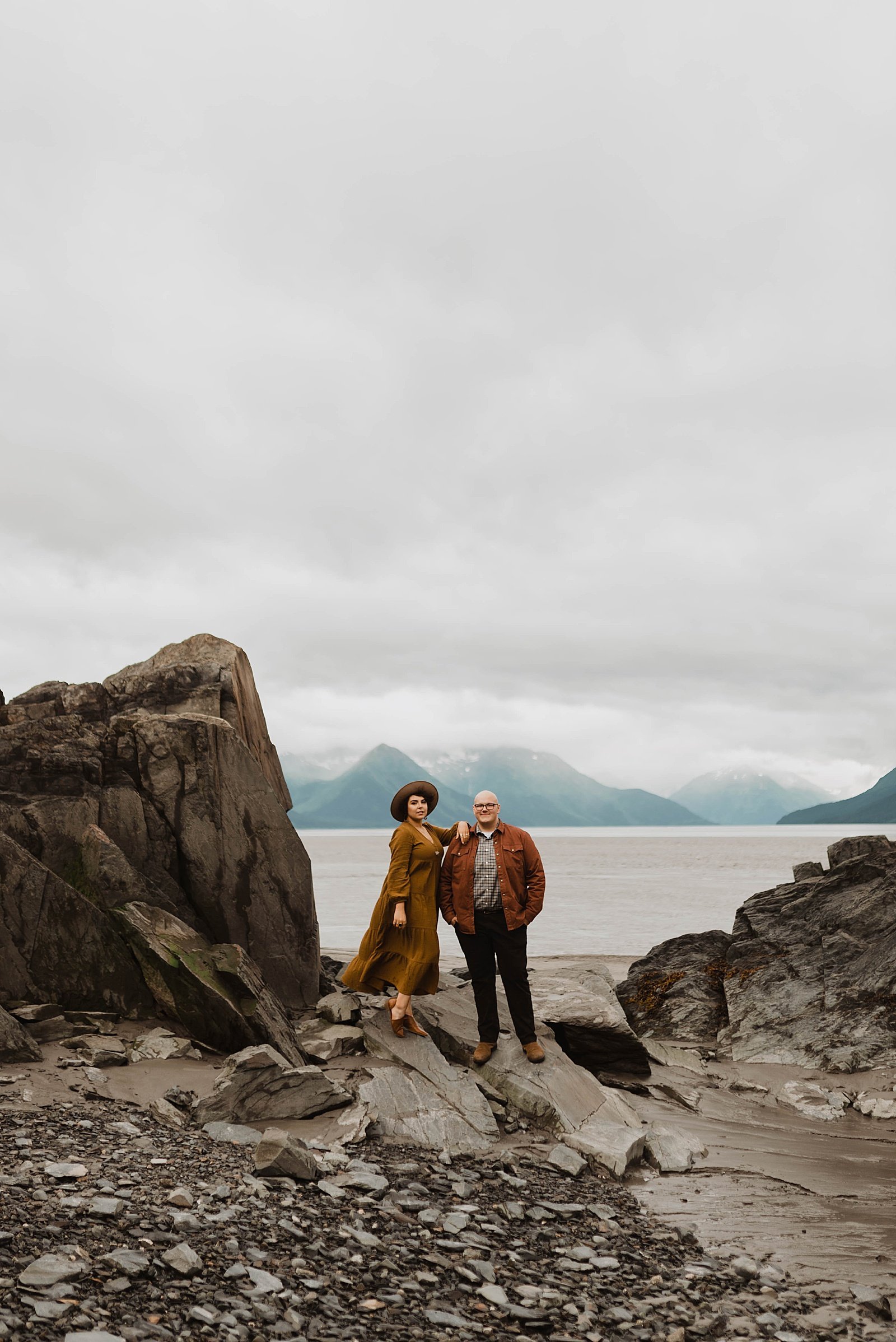  Man and woman in rustic clothing in front of a lake in Alaska for their photo shoot.  