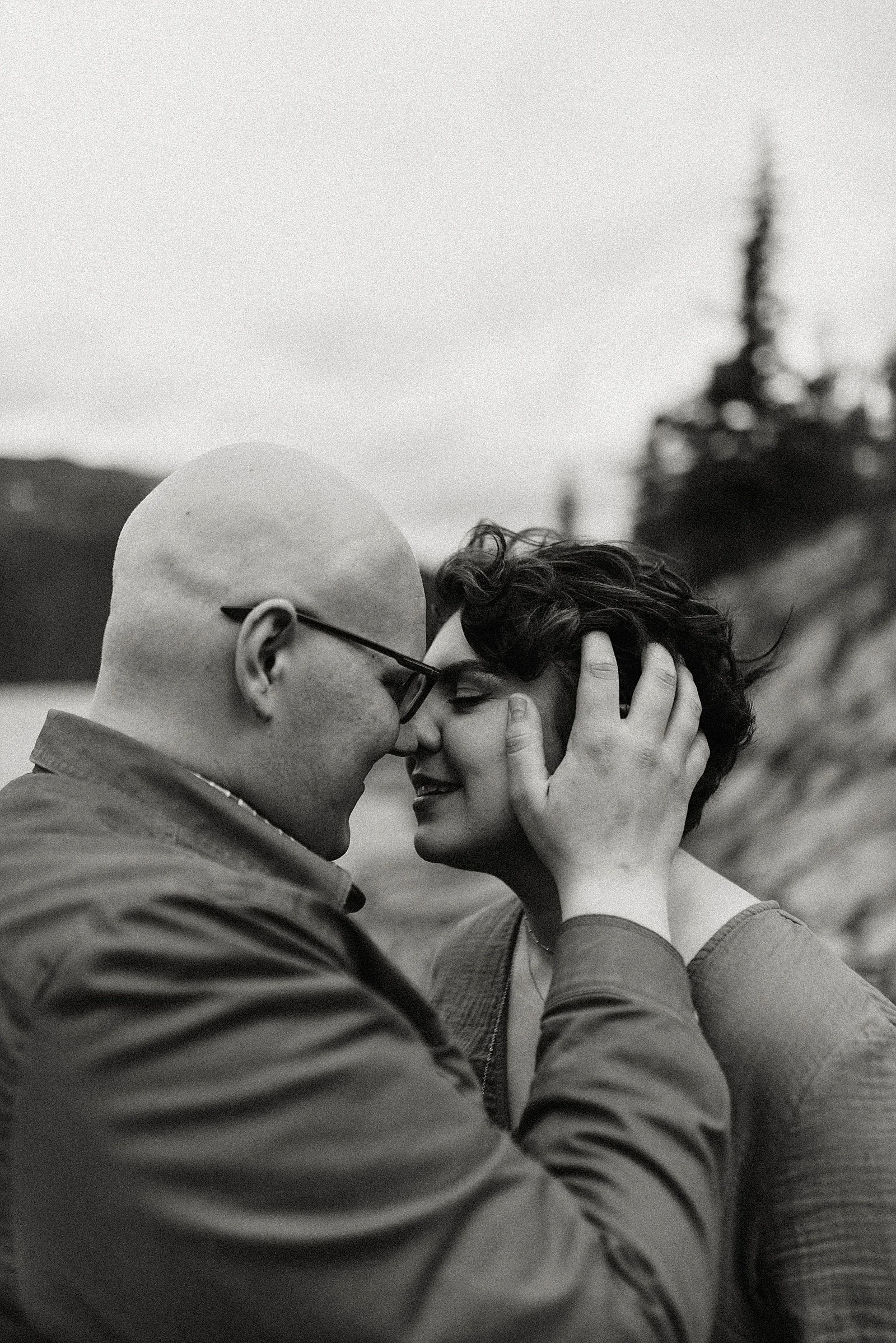 Man holds wife’s face close and snuggles against her nose for their romantic anniversary session.