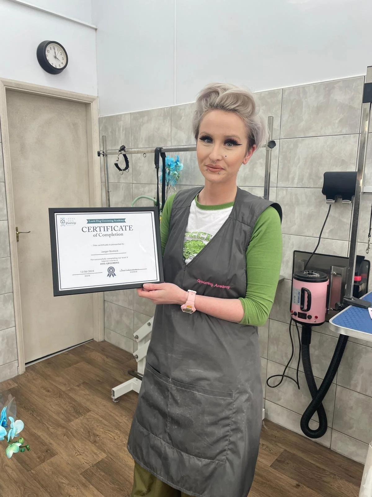 Person in a grooming salon holding a certificate