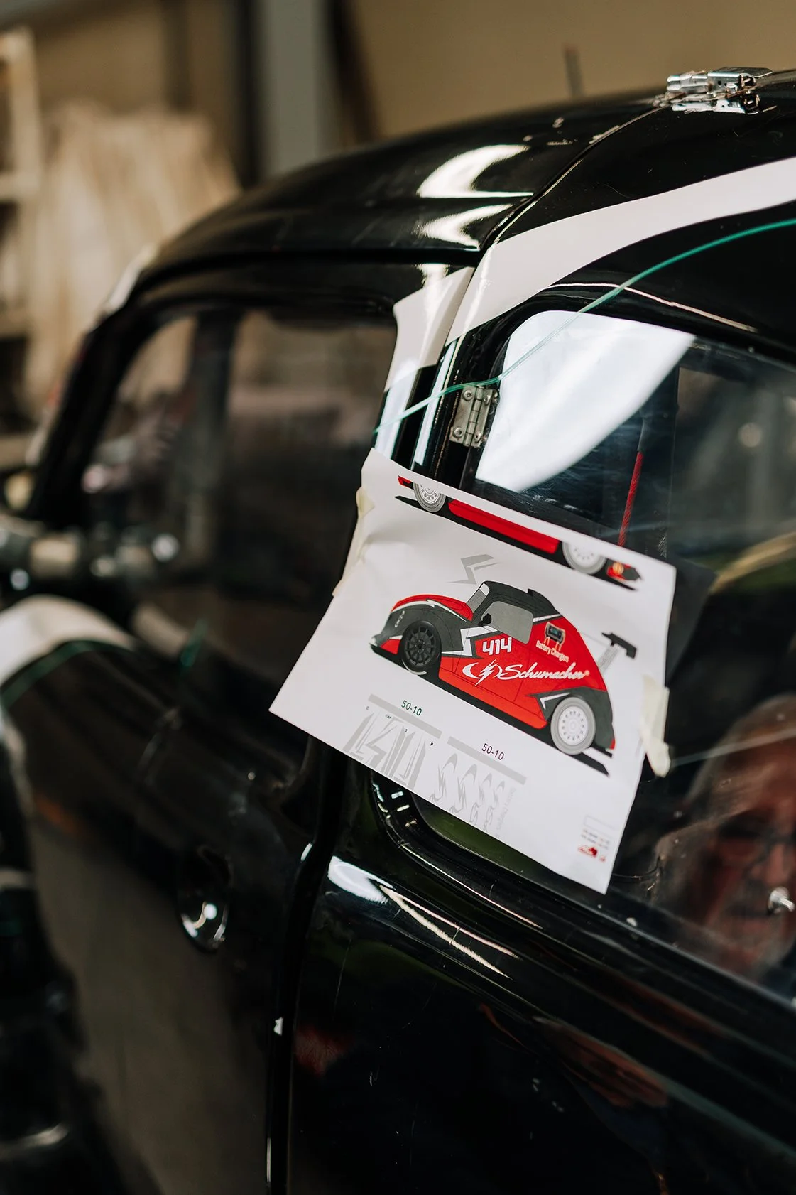 Close-up of a race car with a sticker showing a red and black racing car design, placed on the windshield.