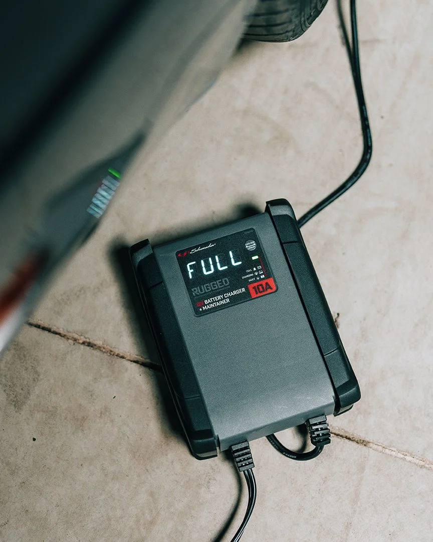 Battery charger with a digital display showing 'FULL' on a tiled floor.